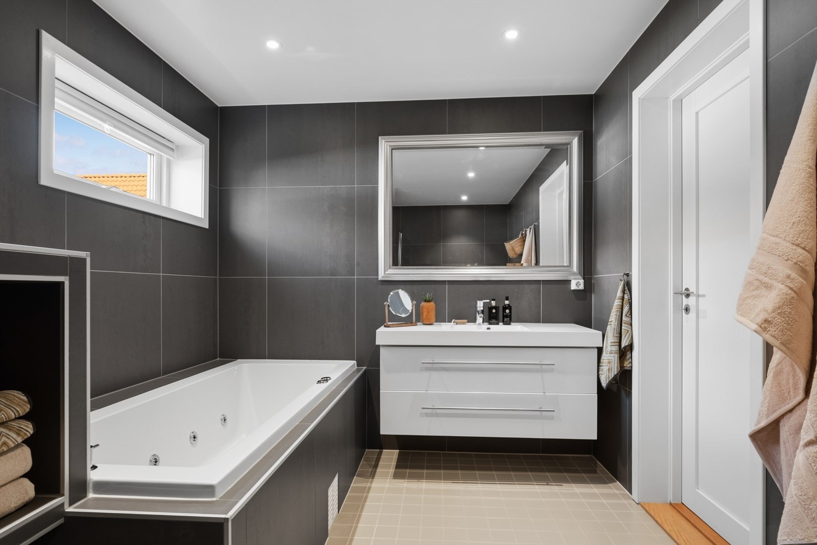 Badet er innredet med baderomsinnredning med heldekkende nedfelt servant med oppbevaring, speil, vegg hengt toalett, badekar og dusjnisje. Galleribilde