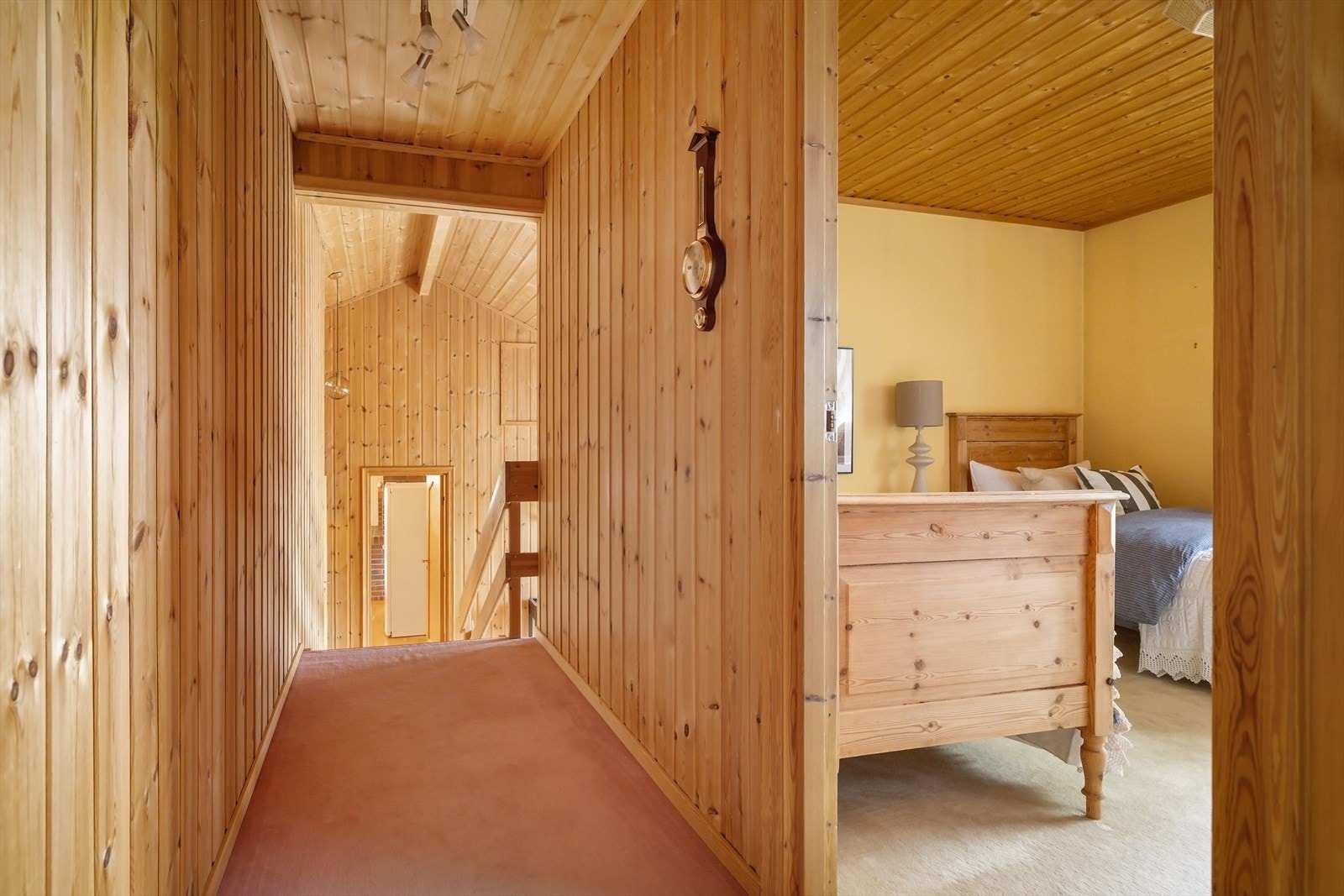 Gang i hovedetasjen med teppe på gulvet og trepanel i himlingen. Galleribilde