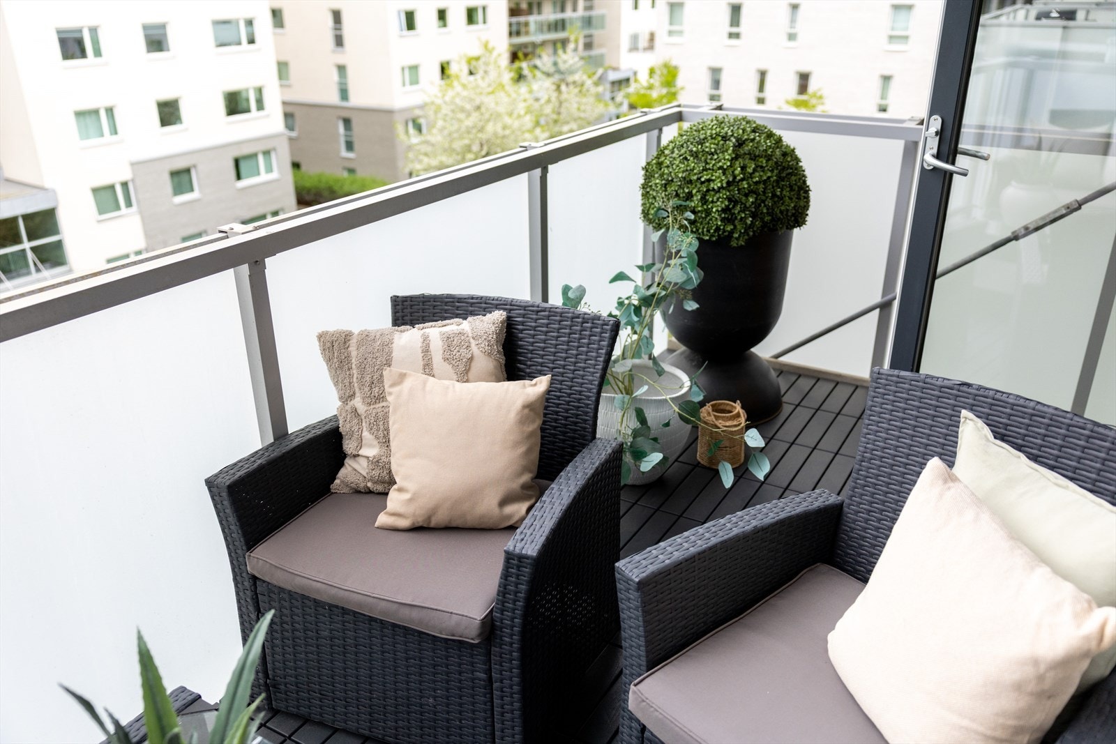 Balkongen fremstår som et hyggelig uteområde med plastfliser på gulv og rekkverk i aluminium med frostede glassfelt som skjermer godt for innsyn. Galleribilde