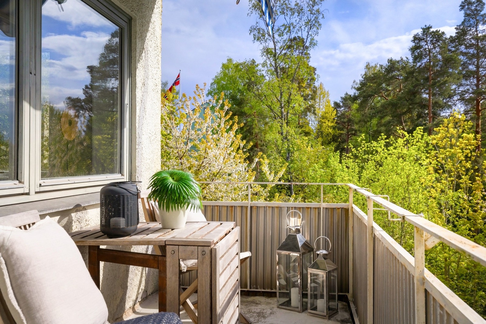 Balkongen omkranses av grønn beplantning og tretopper. Galleribilde