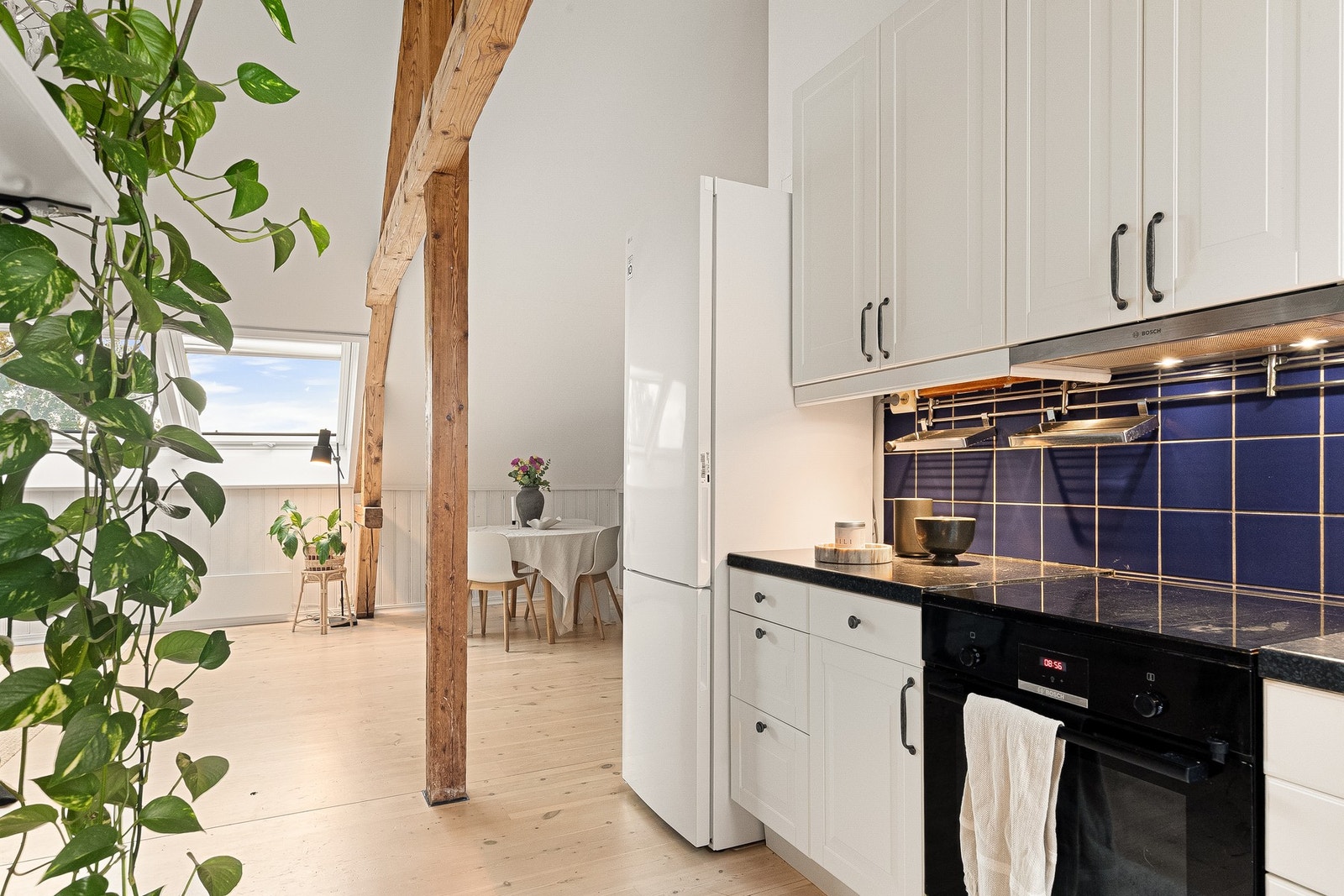 Kjøkkenet har innredning med hvite, profilerte fronter (2026), laminat benkeplate med nedfelt kum i rustfritt stål og uttrekkbar kran. Galleribilde