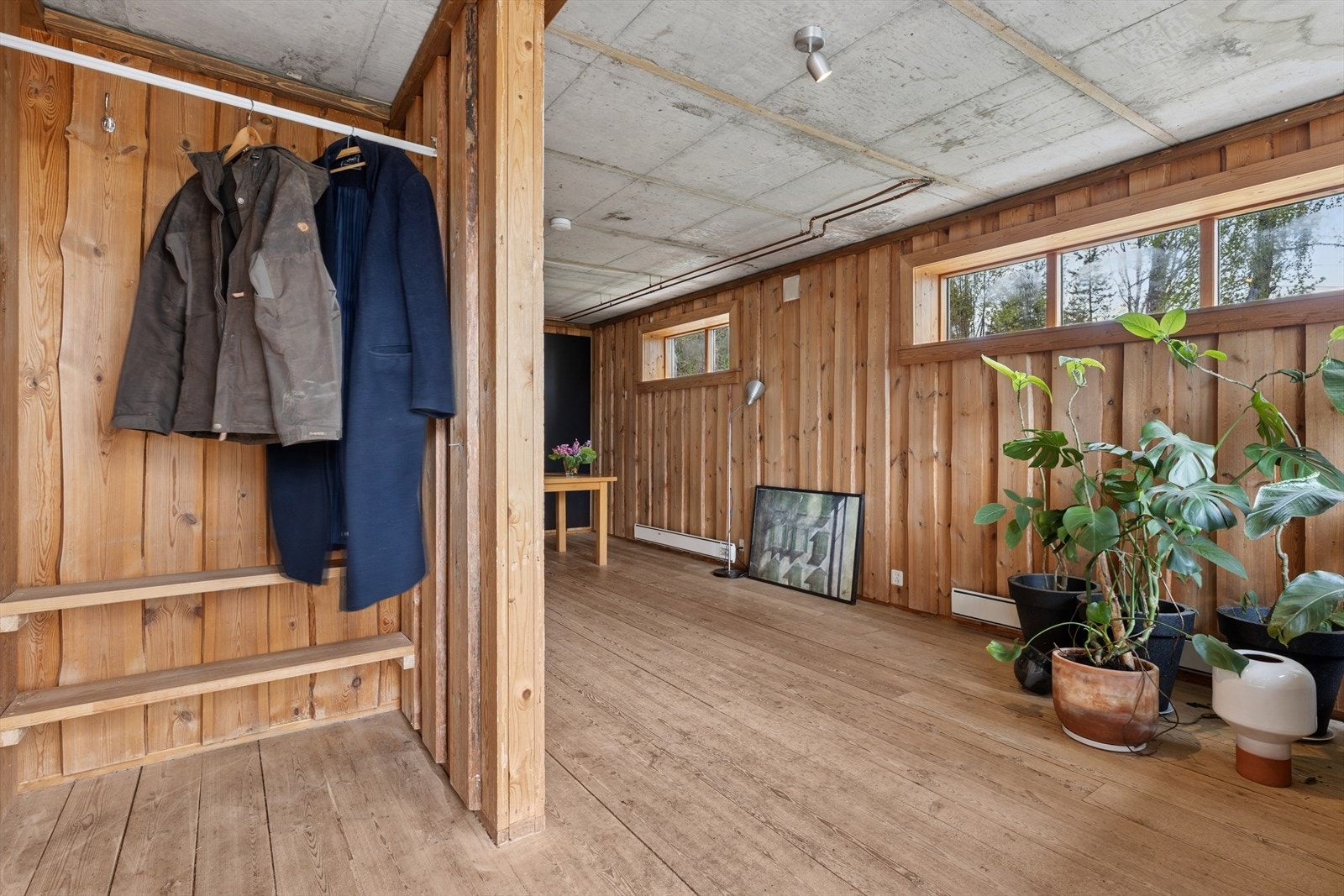 Inngangspartiet i kjelleretasjen har synlig betonghimling og trepanel, som setter tonen for boligens unike stil. Galleribilde