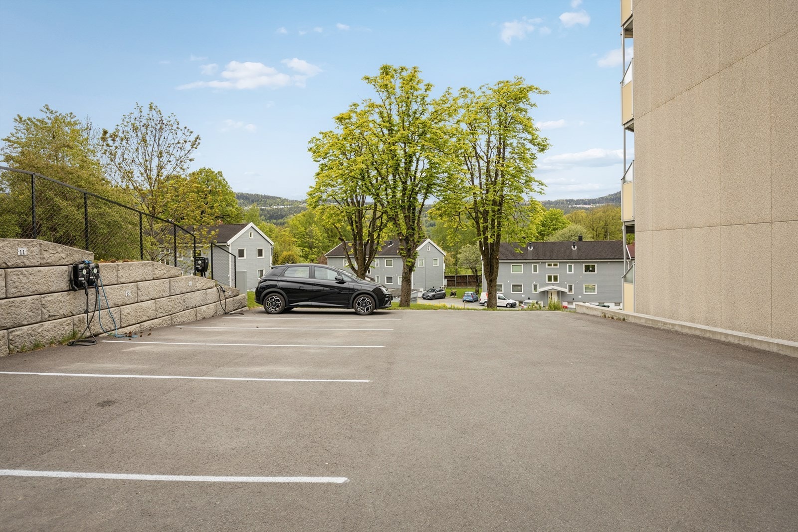 Utvendig parkeringsplass med lader til elbilen. Galleribilde