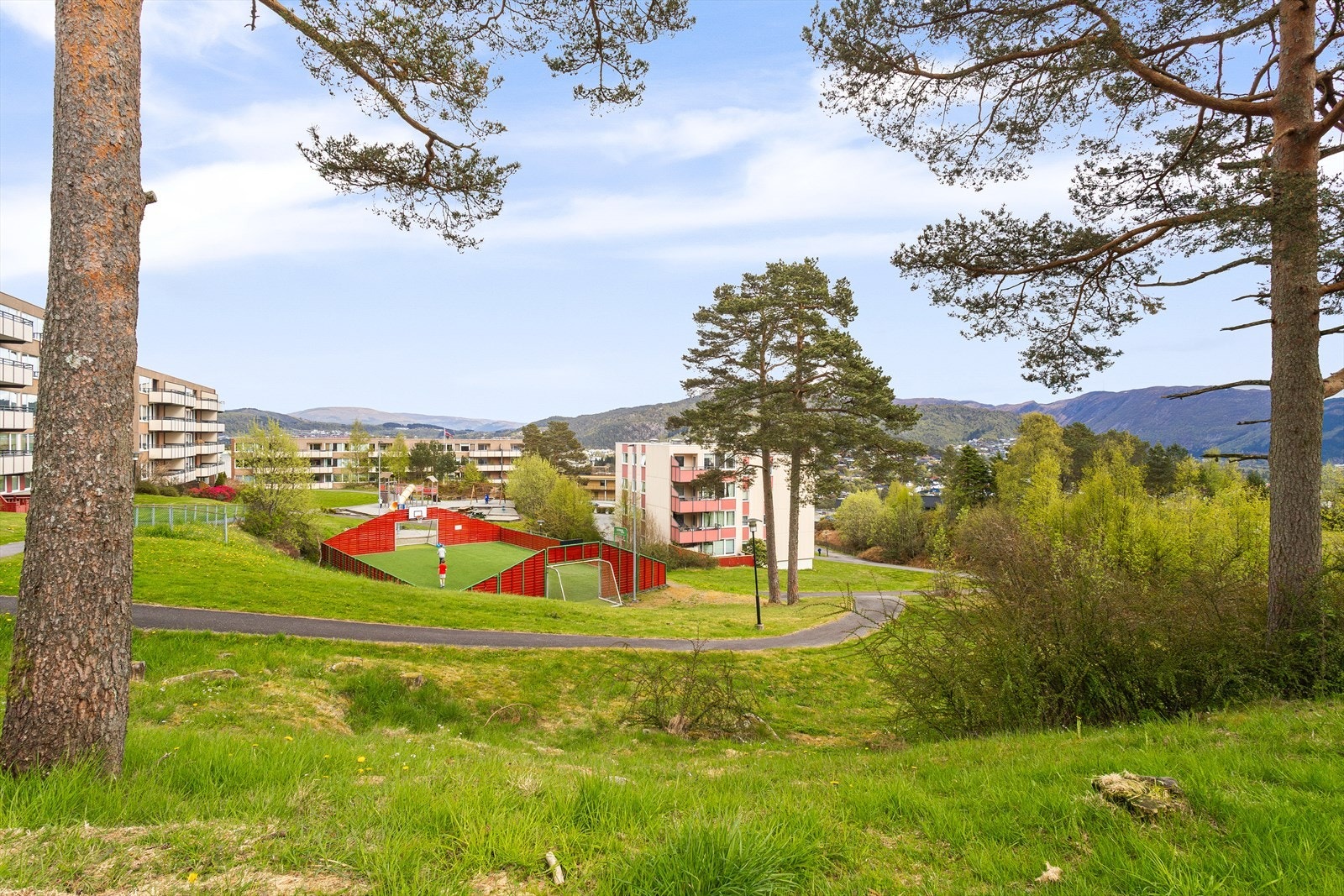 Tomten er for utenom bebyggelsen opparbeidet med interne veier, parkeringsplasser, garasjeanlegg, lekeplasser, ballbinge og diverse plener og beplantninger Galleribilde
