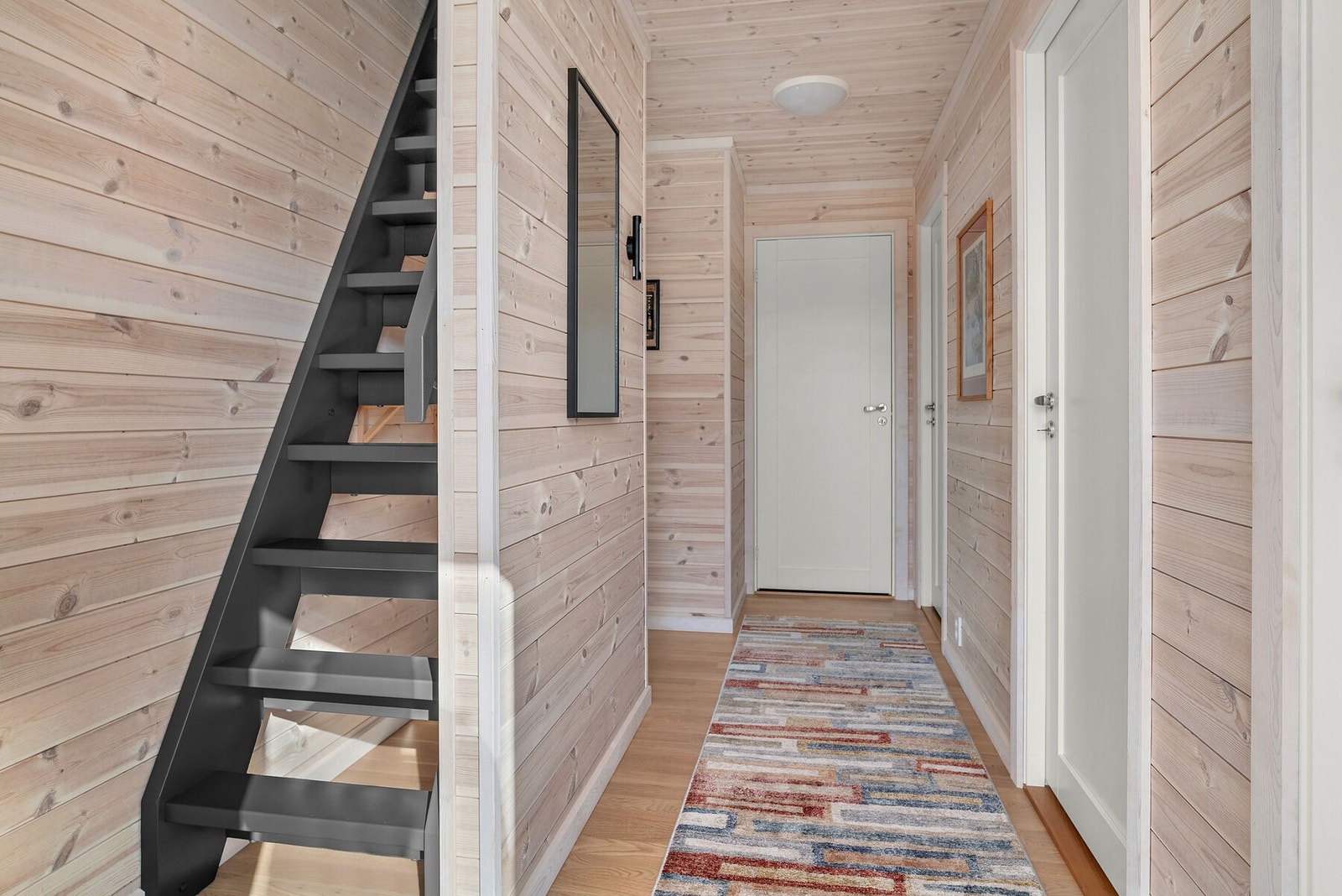 Gjennomgående i hytta er det 3-stavs eikeparkett og hvitlasert sprekkpanel på vegger og i himling. Fra gangen fører en trappestige opp til hemsen. Galleribilde