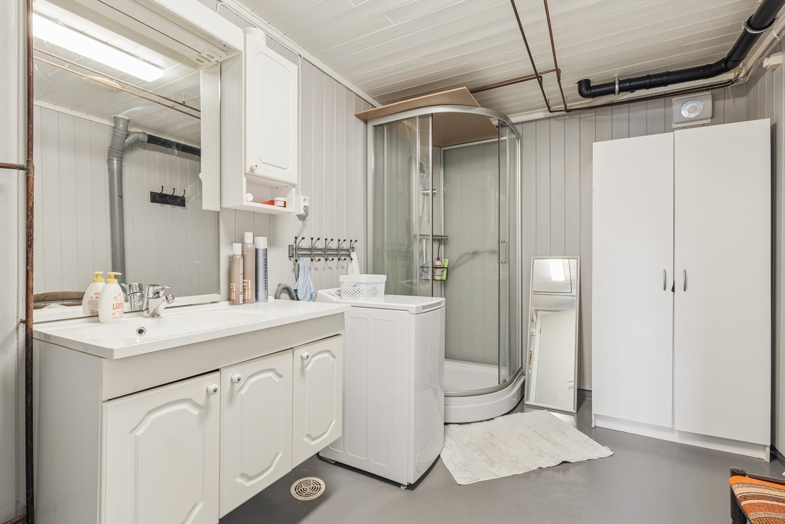 Badet har vinylbelegg med varmekabler og dusjkabinett, men rommet har et oppgraderingsbehov. Galleribilde