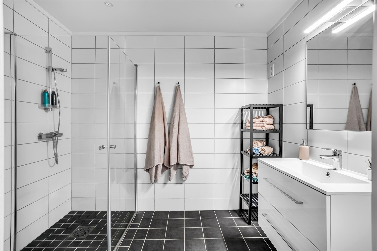 Flislagt bad fra byggeåret med mørke gulvfliser og hvite veggfliser. Det er varme i gulvet. Galleribilde