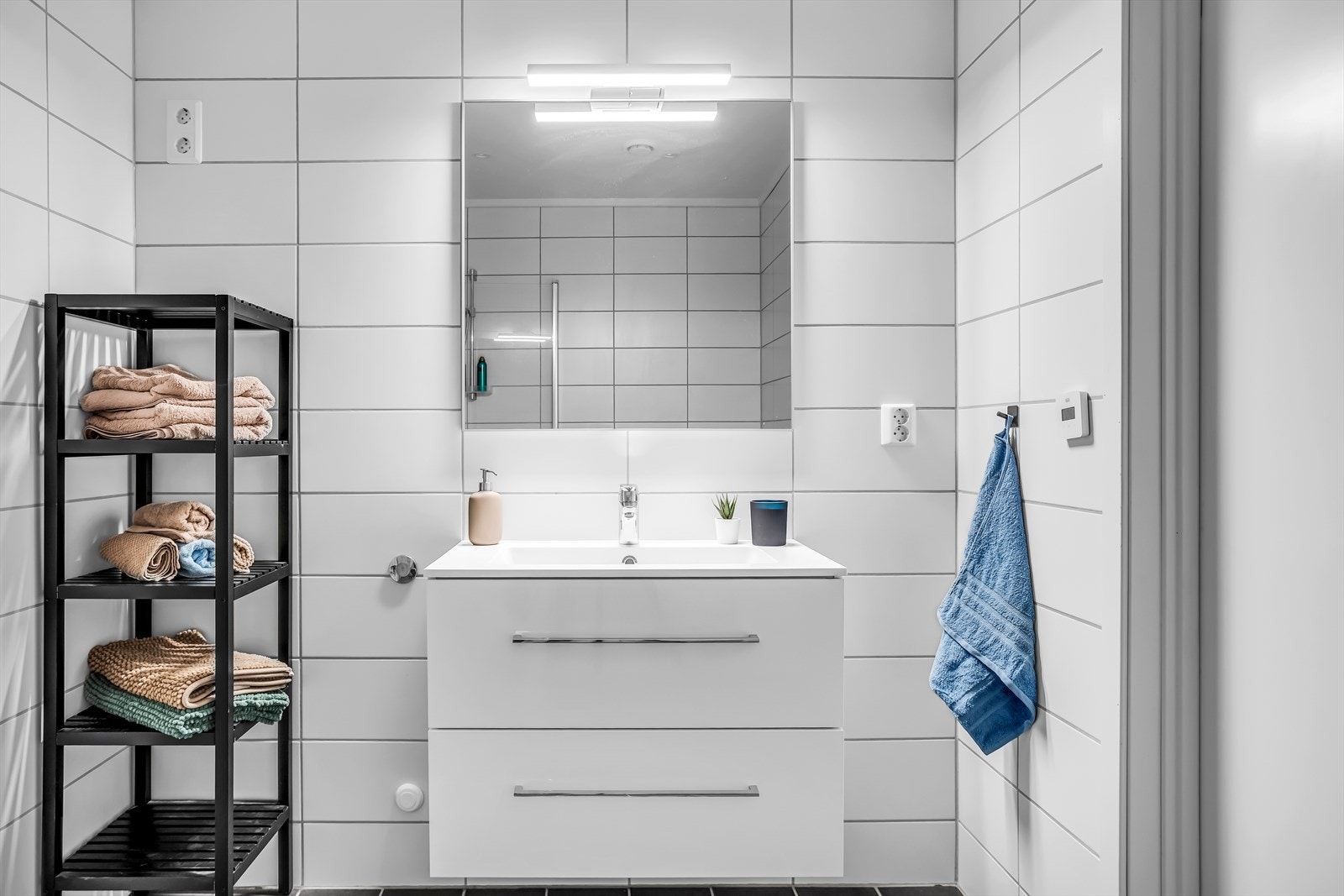 Baderomsinnredning med glatte, hvite fronter og belyst speil. Galleribilde