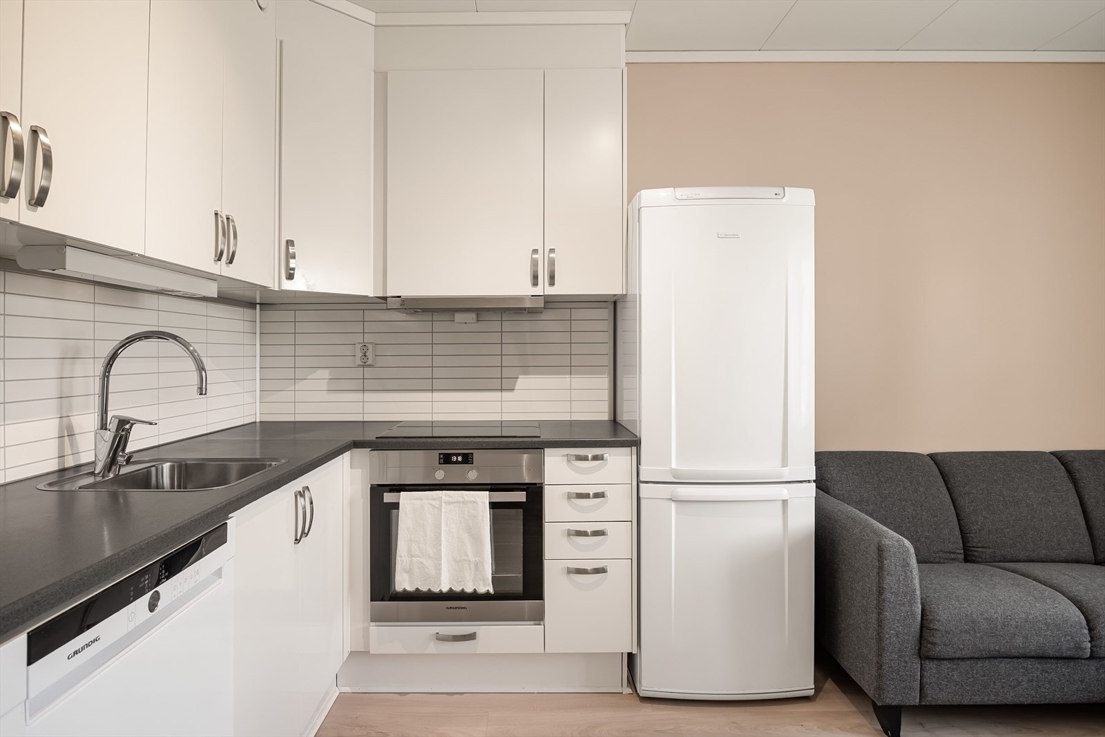 Innredningen har hvite glatte fronter og laminert benkeplate med nedfelt oppvaskkum. Praktisk med lyse flisimitasjonsplater i benkeryggen og belysning under overskapene. Galleribilde