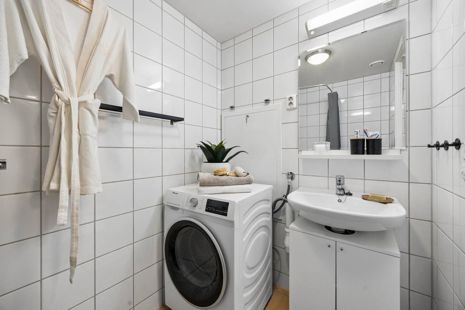 Badet har servantinnredning med plane fronter, gulvmontert toalett og kran og avløp for vaskemaskin. Galleribilde