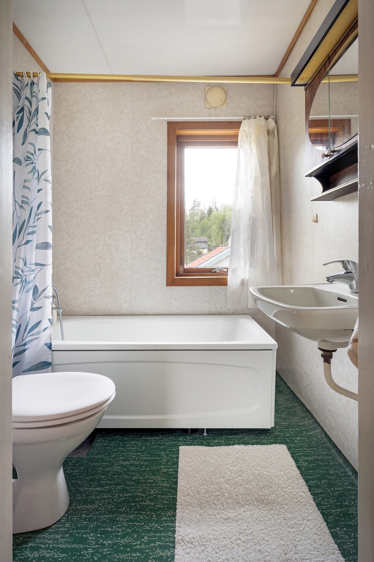 Badet er innredet med badekar, toalett og servant med speilskap over. Galleribilde