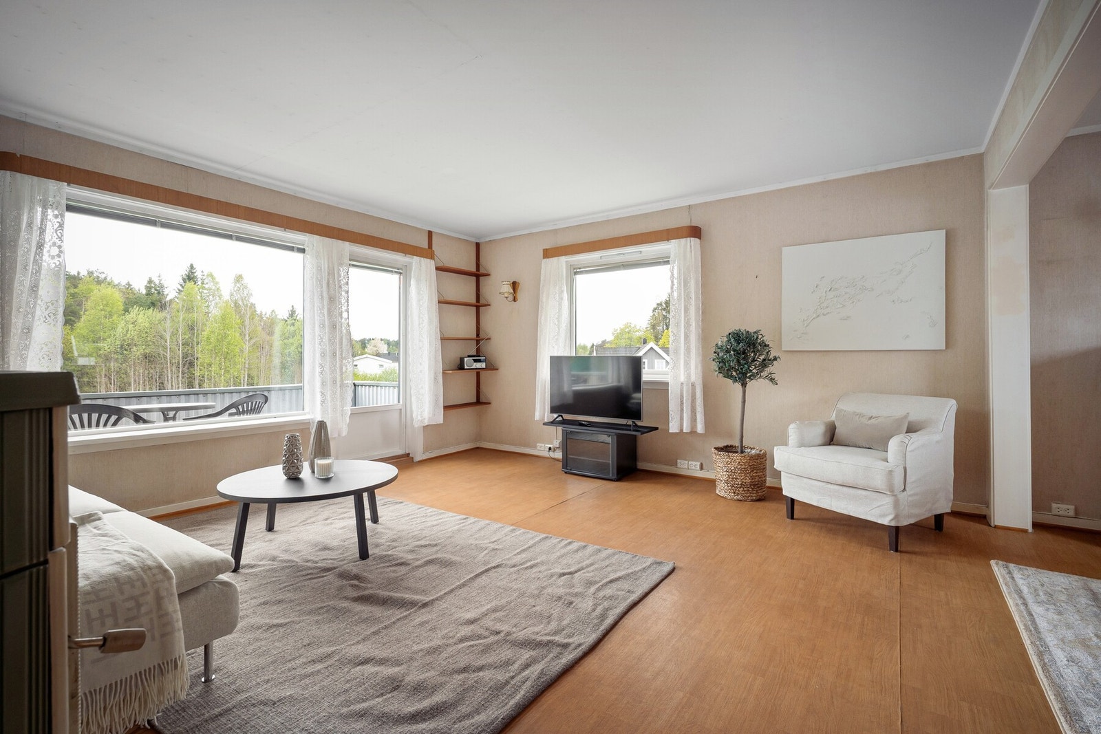 Romslig og lys stue med store vindusflater som slipper inn godt med naturlig lys og gir utsyn mot grønne omgivelser. Galleribilde