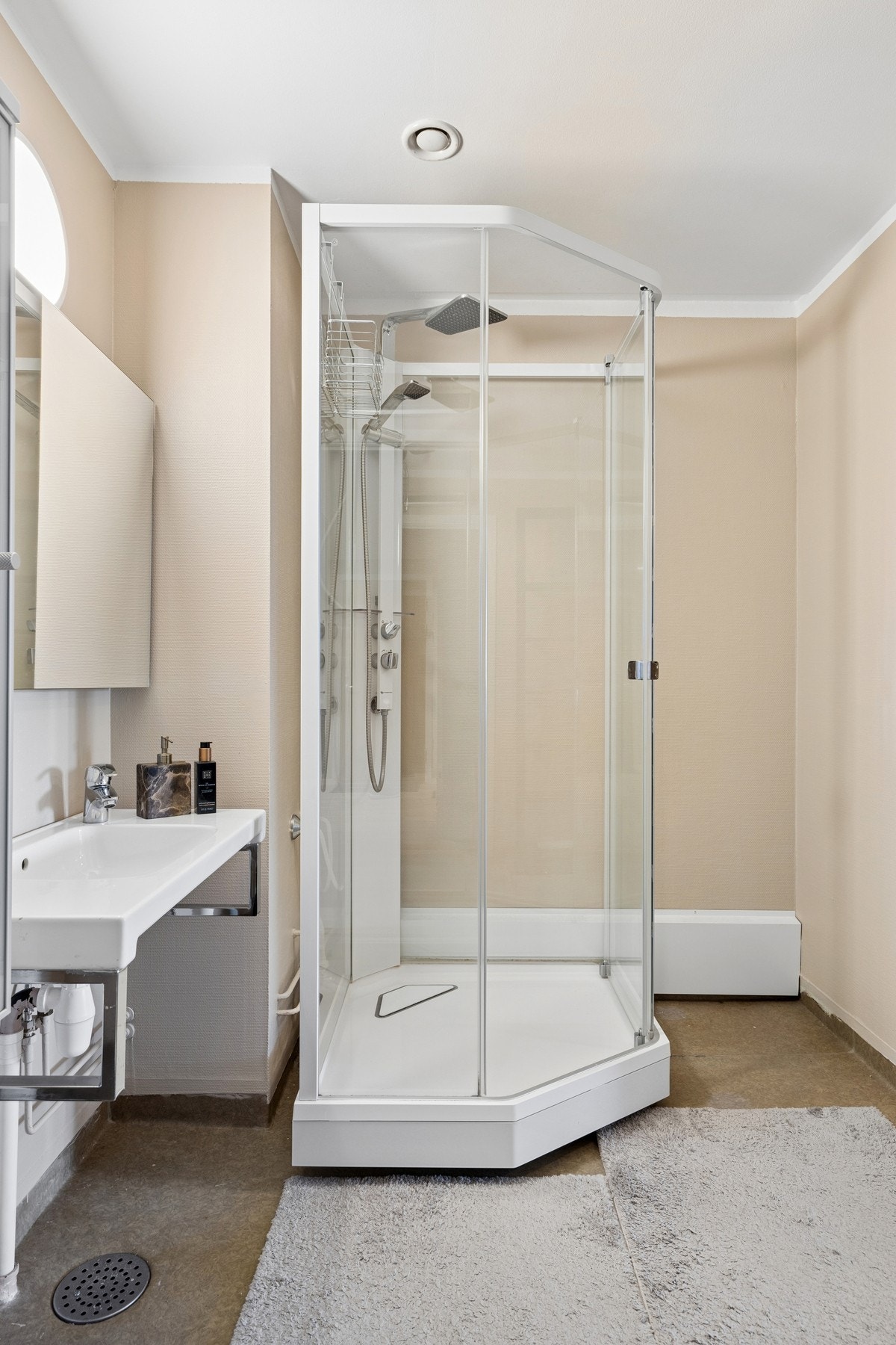 Badet er utstyrt med dusjkabinett og baderomsinnredning. Overflatene er fra byggeår. Galleribilde