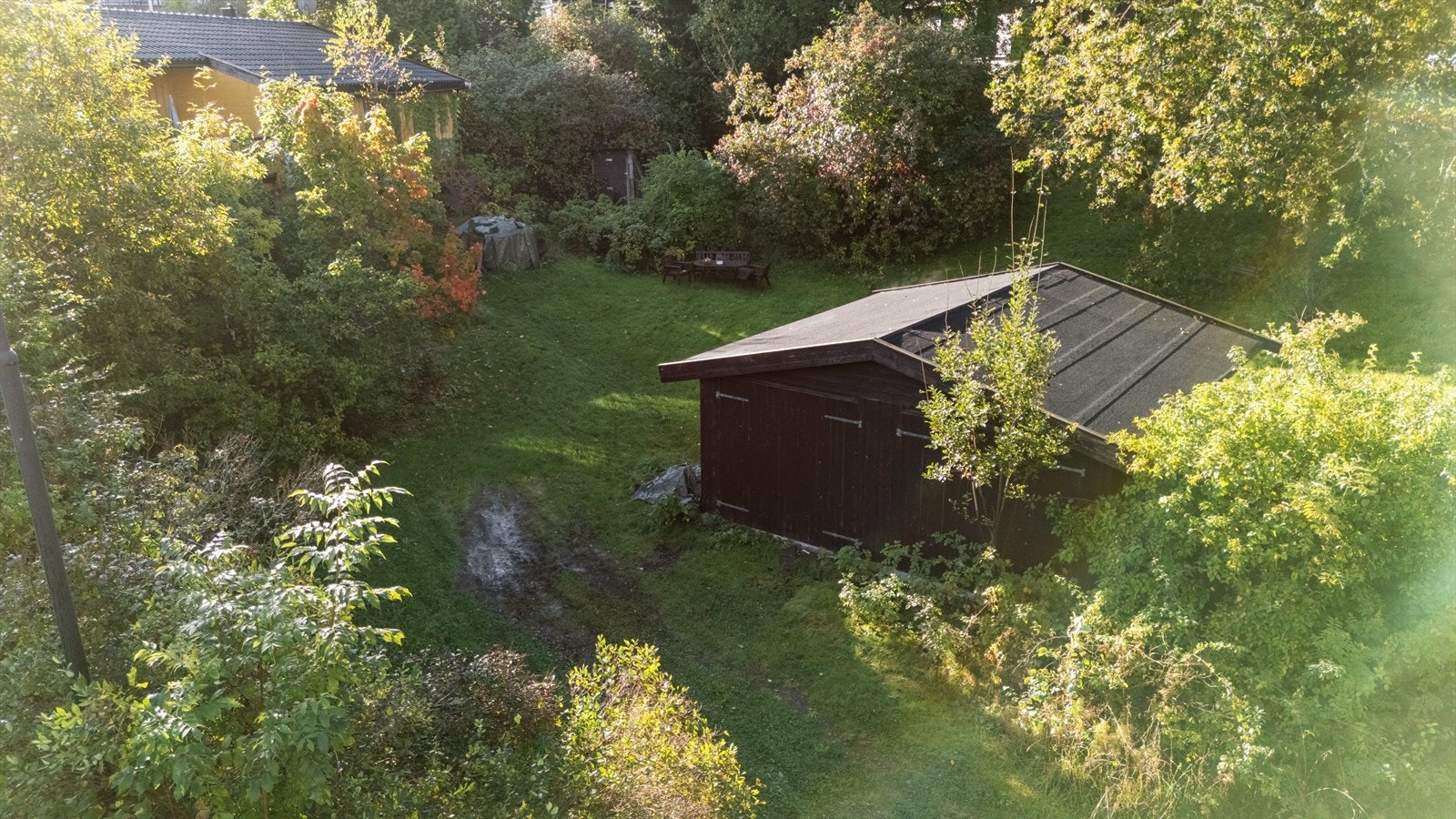 Tomten fremstår som delvis naturpreget med innslag av både plen og lett skrånende terreng, noe som skaper flere fine soner for uteopphold og rekreasjon. Galleribilde