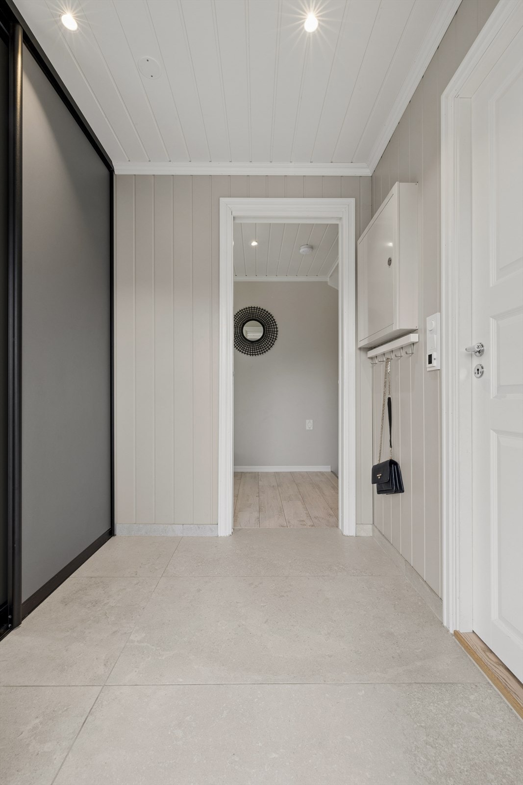 Du kommer inn i en lys og innbydende gang med fliser på gulv og godt med lagring i skyvedørsgarderobe. Galleribilde