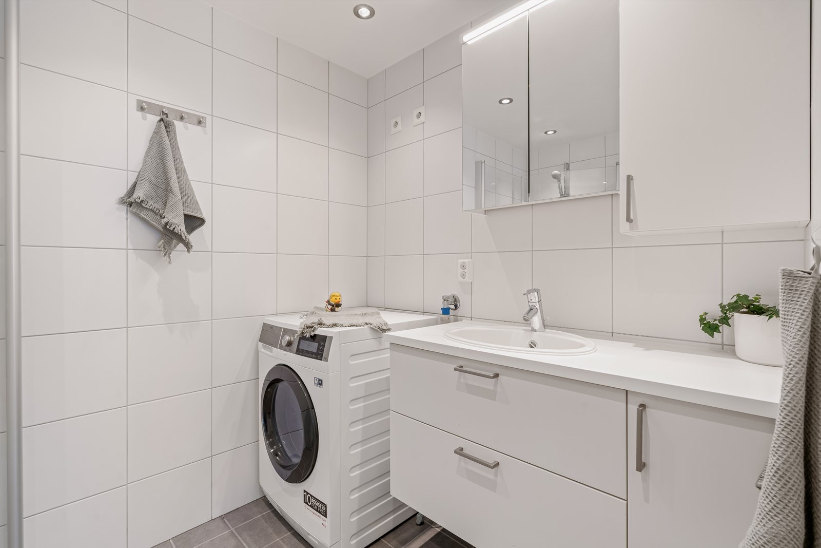 Vannbåren gulvvarme gir god komfort og en behagelig varme året rundt. Badet er funksjonelt utformet og har praktisk opplegg for vaskemaskin, noe som gjør det godt tilpasset hverdagsbruk. Galleribilde