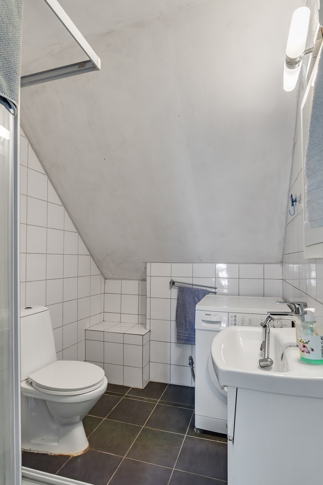 Badet inneholder dusjkabinet, toalett, innredning med servant og opplegg for vaskemaskin Galleribilde