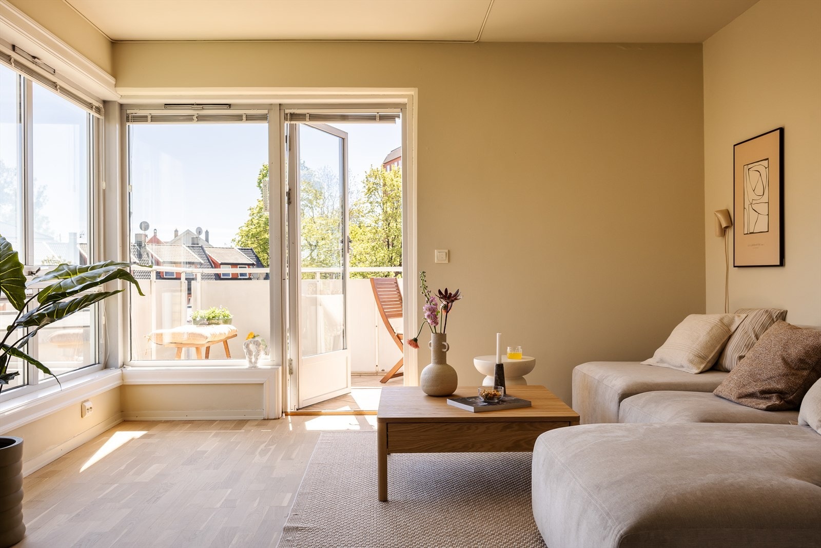 Lys og pen stue med plass sofa og sofabord. Store vinduer og utgang til solfylt balkong. Galleribilde