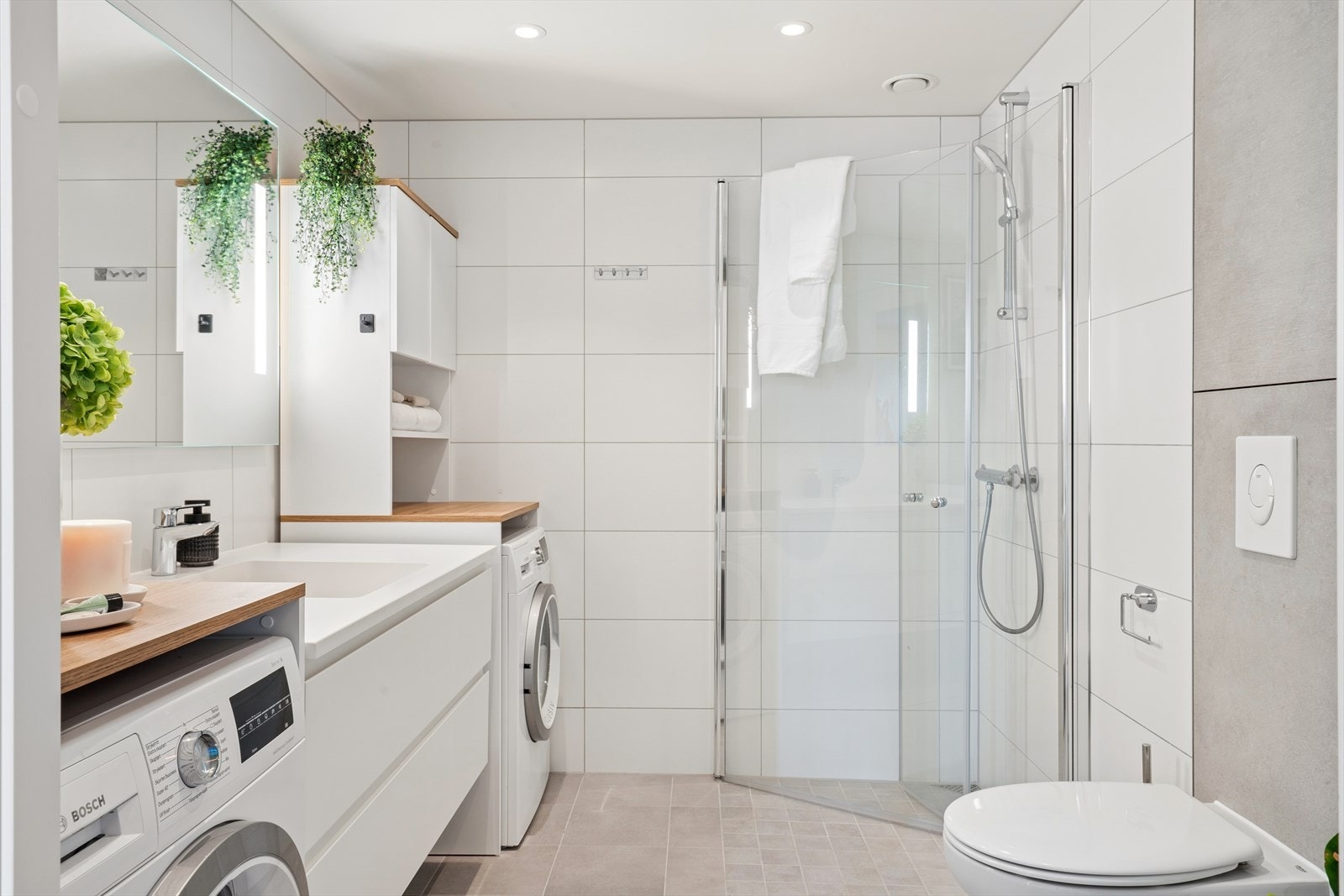 Hovedbadet på 5,5 kvm er flislagt og er utstyrt med dusj, nedfelt servant med underskap, WC og downlights i himling. Her er det også opplegg for vaskemaskin og tørketrommel Galleribilde
