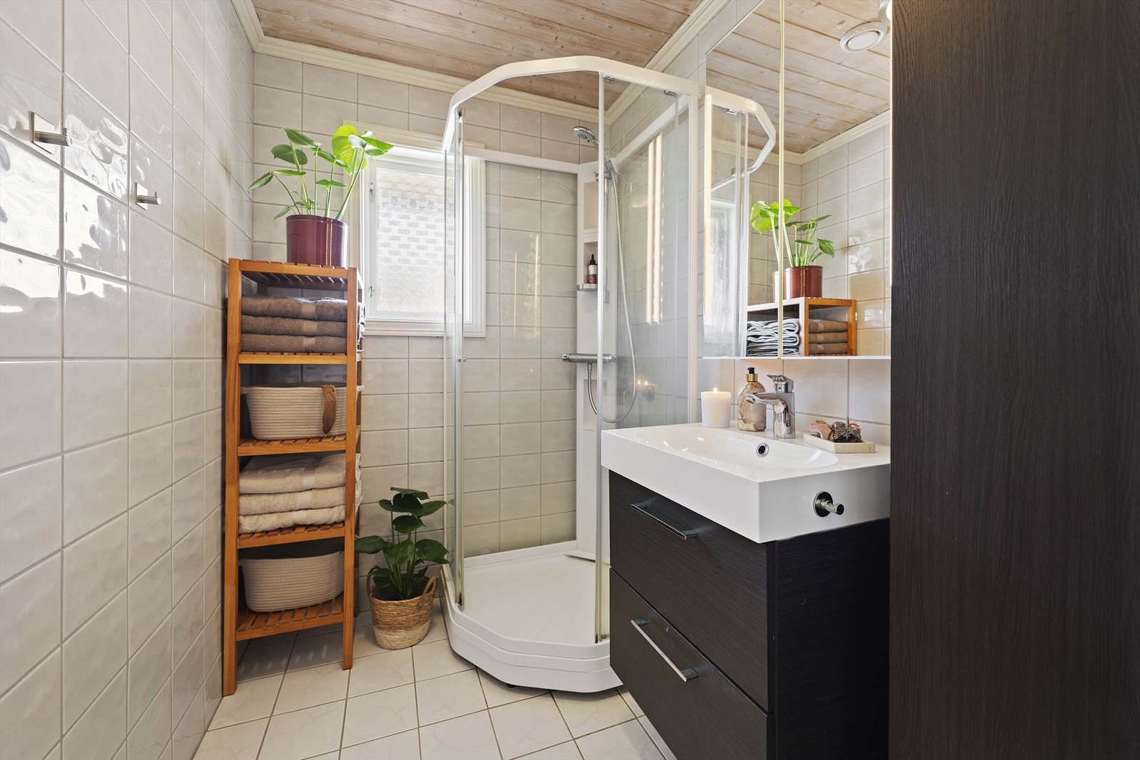 Lyst, helfliset baderom med varmekabler i gulv. Badet er utstyrt med servant over skuffeinnredning, speilskap, vegghengt skap og dusjkabinett Galleribilde