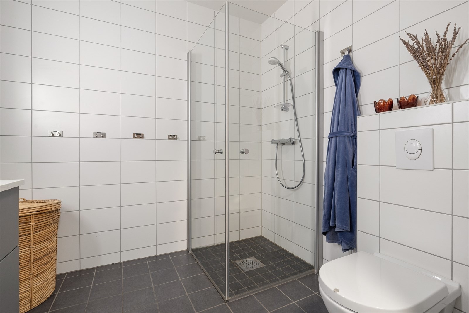 Badet er blant annet utstyrt med veggmontert toalett, dusjhjørne og servant med tilhørende skuffeinnredning. Galleribilde