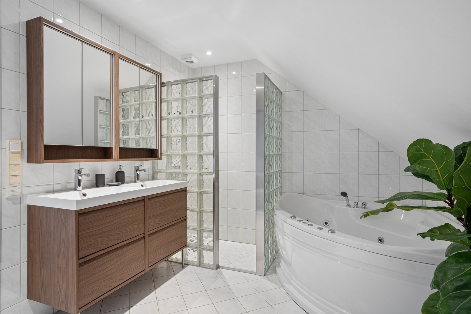 Badet er utstyrt med både dusjnisje av glassbyggerstein og et hjørnebadekar med massasjefunksjon. Galleribilde