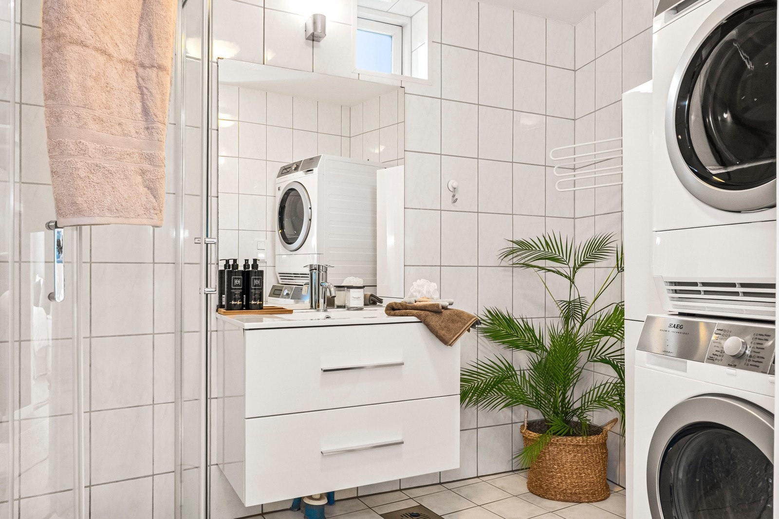 Lyst og flislagt bad med praktisk dusjløsning og opplegg for vaskemaskin og tørketrommel. Galleribilde