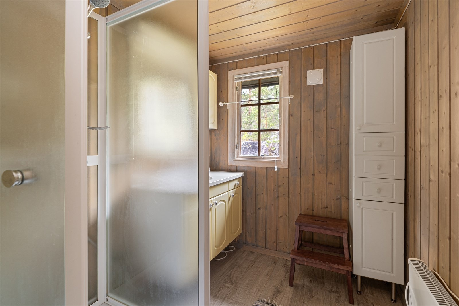 Badet er utstyrt med dusjkabinett, servantinnredning og har vinylbelegg på gulvet. Galleribilde