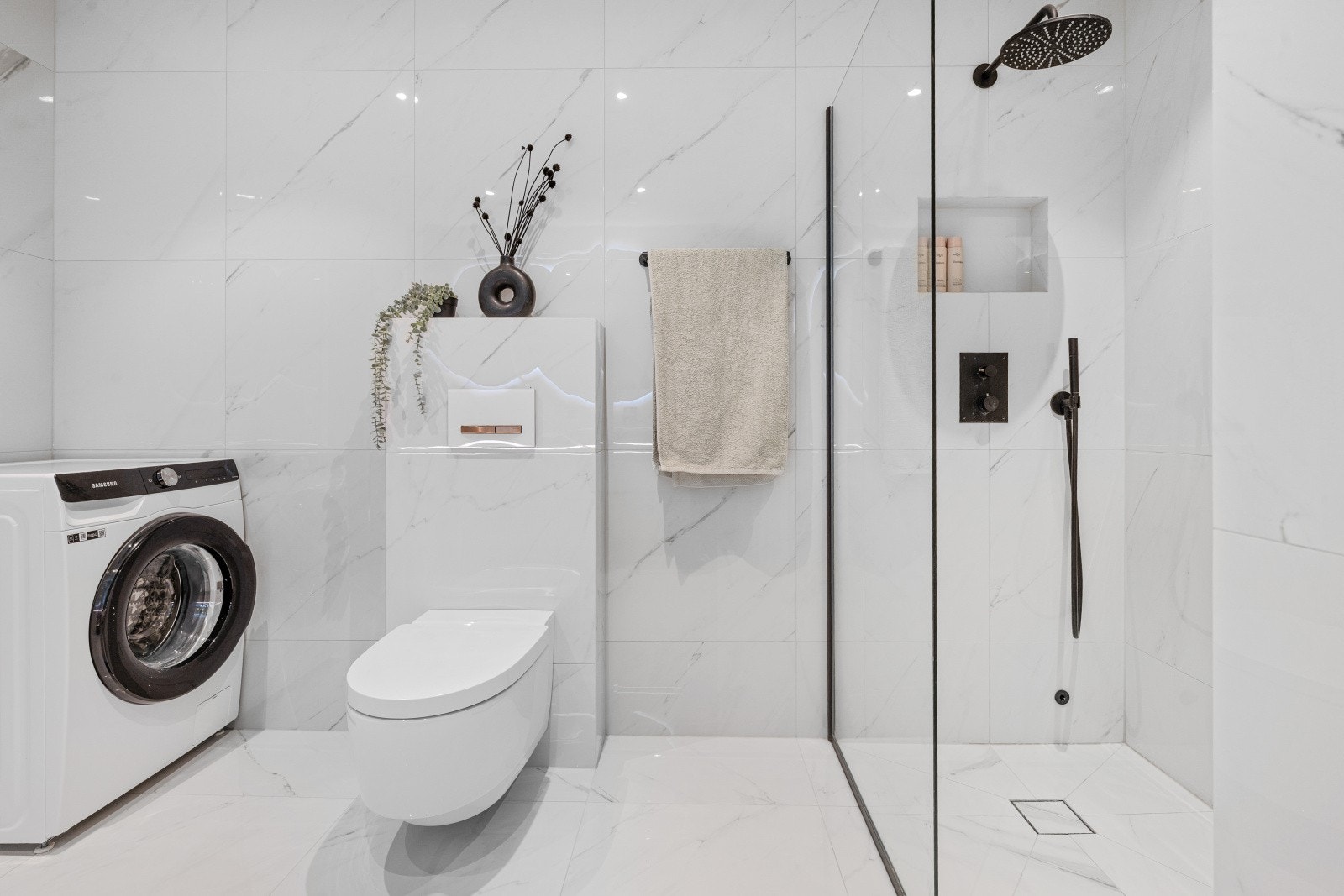 Opplegg for vaskemaskin. Ellers oppgraderte marmoreffekt fliser, samt. regndusj og dusjvegg. Toalett av merket Geberit Aquaclean. Galleribilde