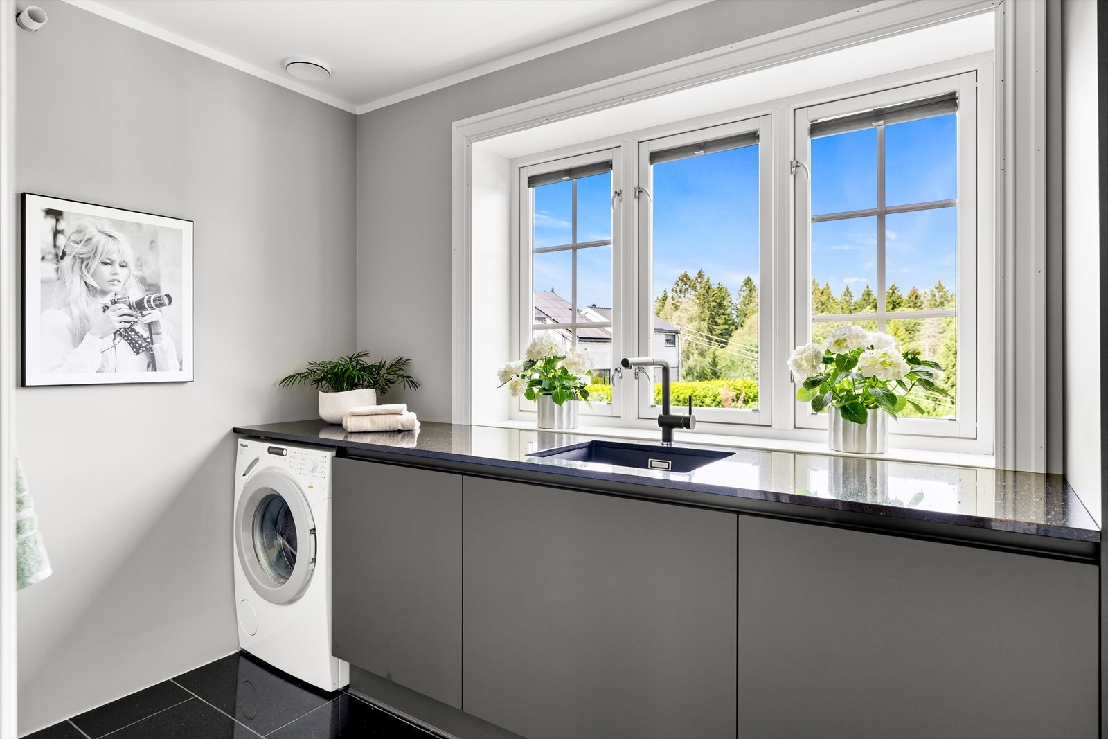 Av innredning er det grå underskap, og over ligger det en sort benkeplate i granitt med underlimt, sort kum. Under benken er det også opplegg og plass for vaskemaskin. Galleribilde