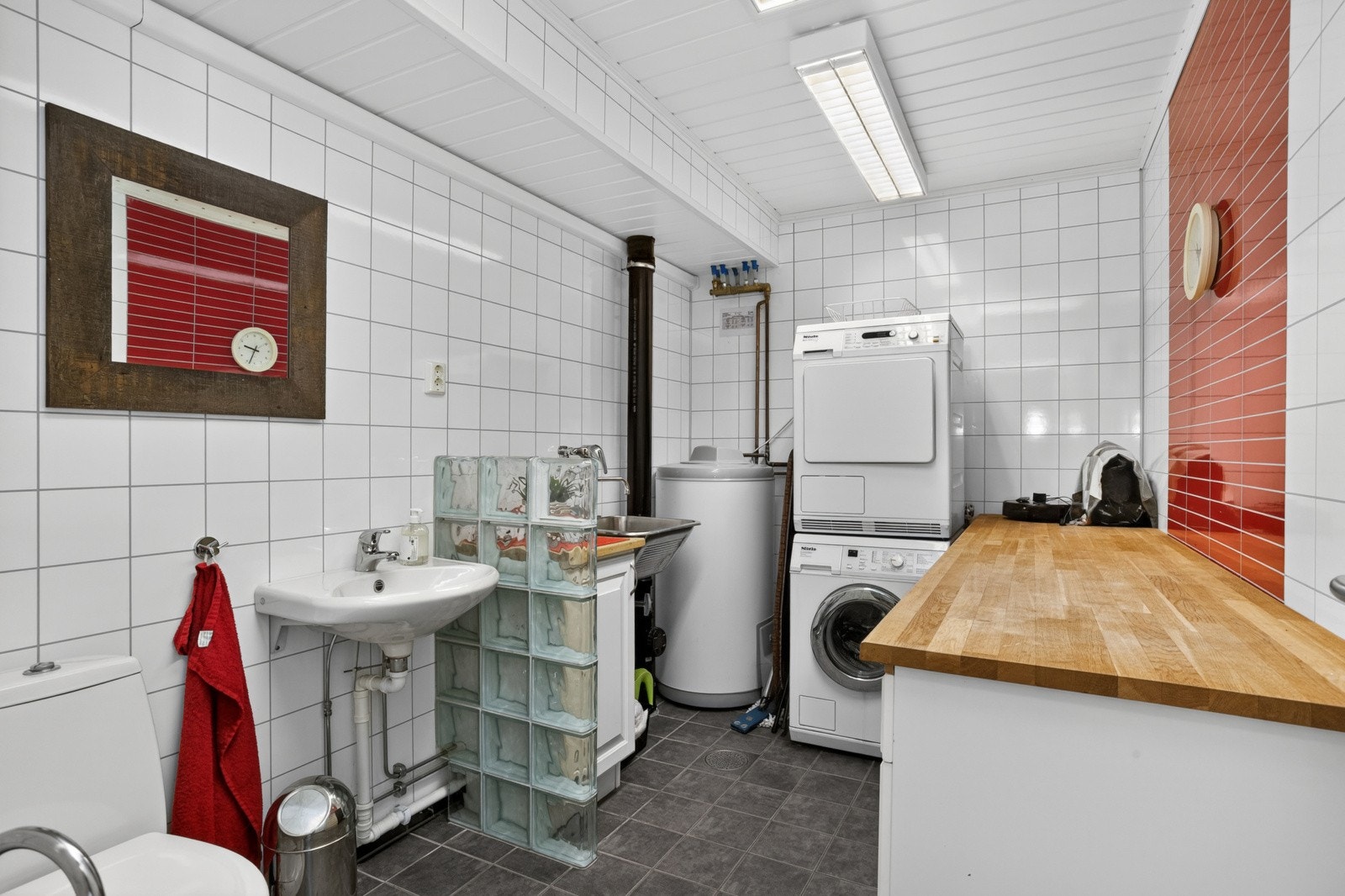 Praktisk vaskerom i første etasje med flislagt gulv med varmekabler, opplegg for vaskemaskin og god benkeplass. Galleribilde