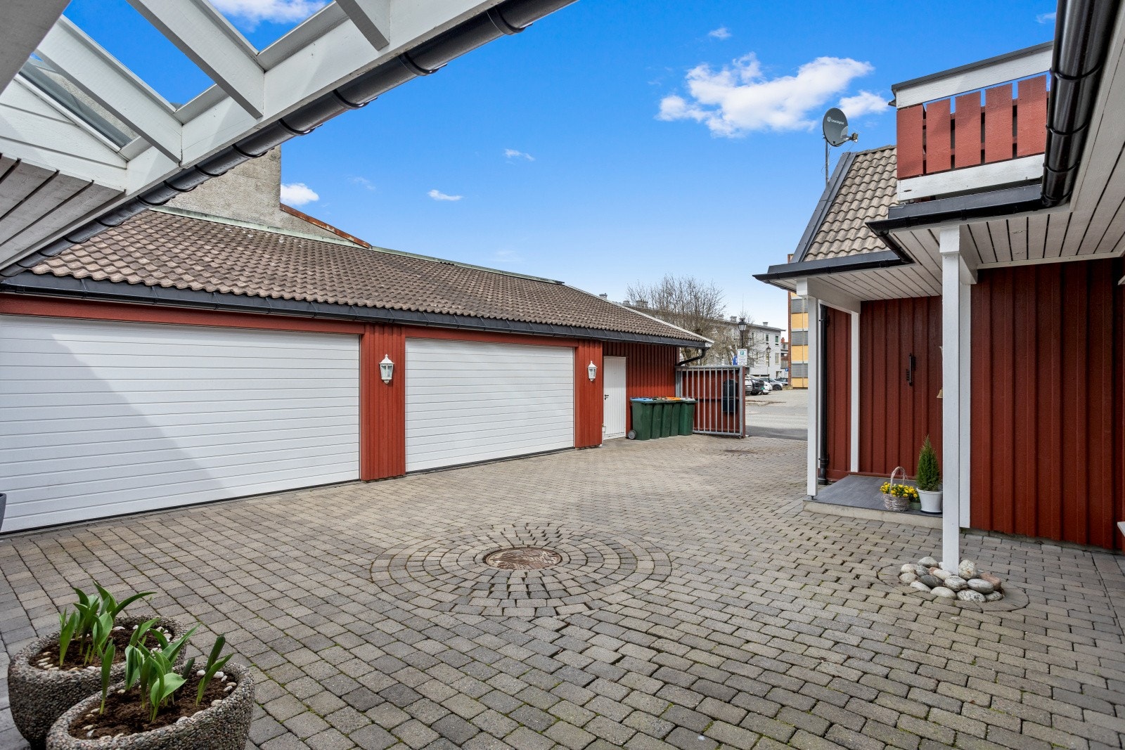 Garasjeanlegget har vegger av bindingsverk kledd med panel og tak tekket med dobbeltkrummet betongstein. Galleribilde