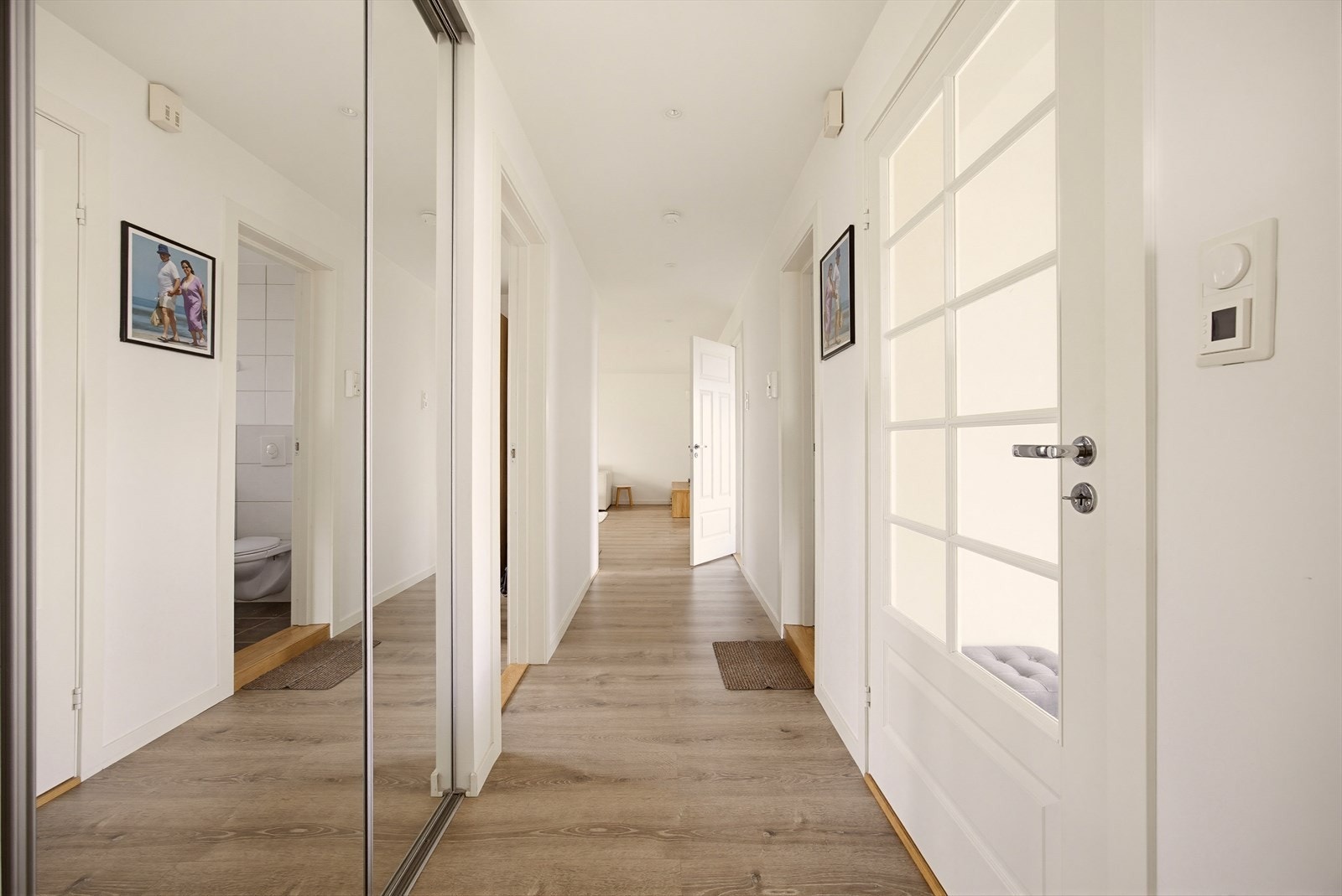 En dør med glassfelt skiller gangen og entréen. Gangen byr på stor skyvedørsgarderobe med plass til alle ytterklær og sko. Galleribilde