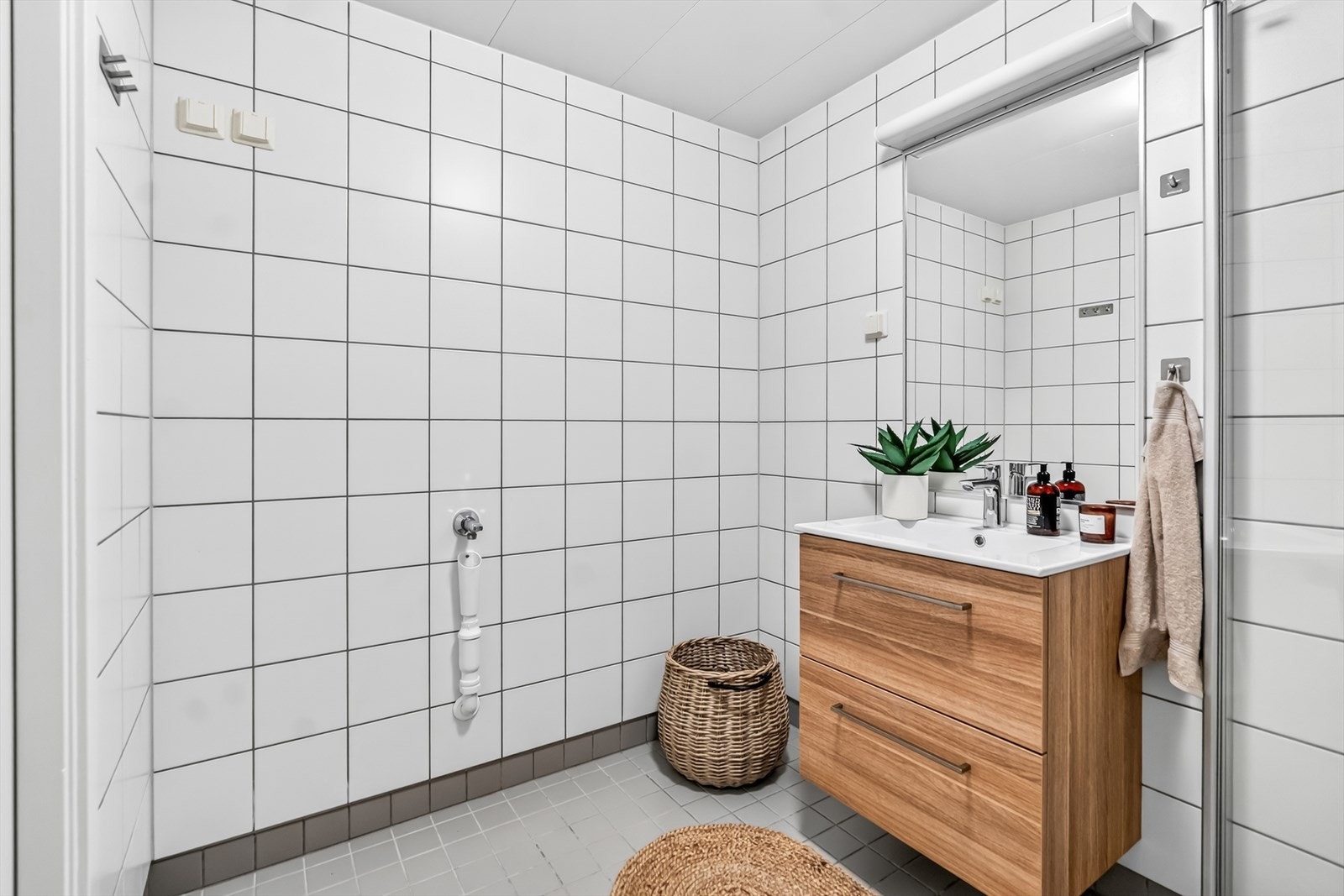 Badet er utstyrt med vegghengt toalett, dusjsone med glassvegger, servant med oppbevaringsmuligheter samt opplegg for vaskemaskin. Galleribilde