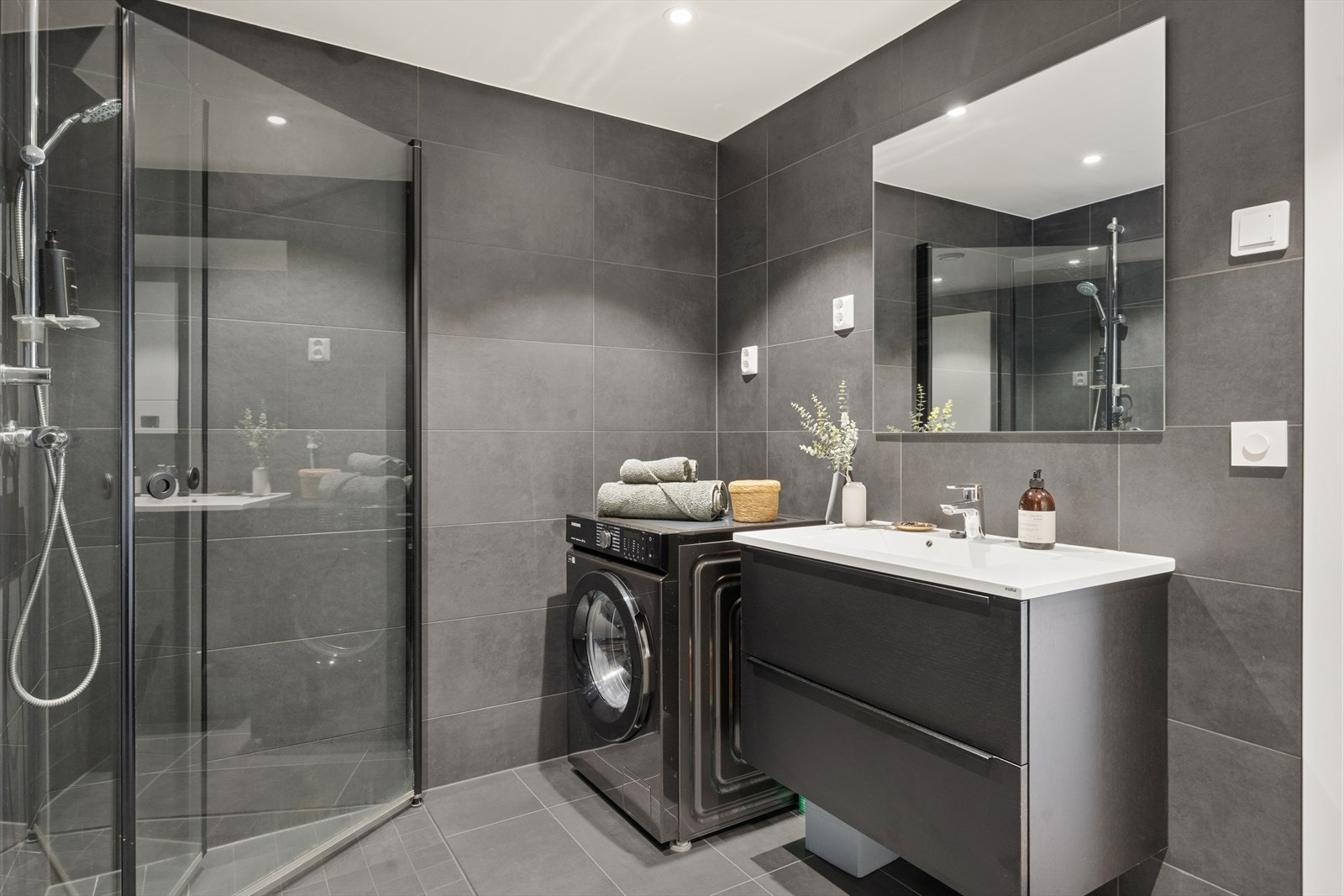 Badet som er fra byggeår fremstår som moderne, godt utnyttet med innfellbare dusjdører, toalett, servant med tilhørende underskap og opplegg for vaskemaskin. Galleribilde