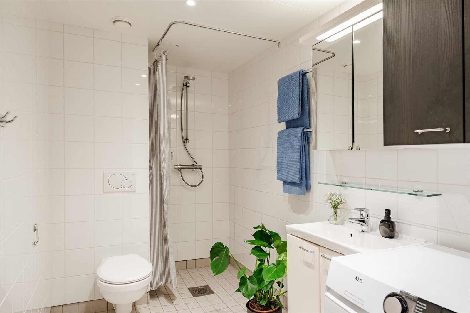 Badet består av toalett, dusj, servant med underskap og opplegg til vaskemaskin. Mekanisk avtrekk fra baderommet er tilknyttet bygningens felles mekaniske avtrekksventilasjon. Galleribilde