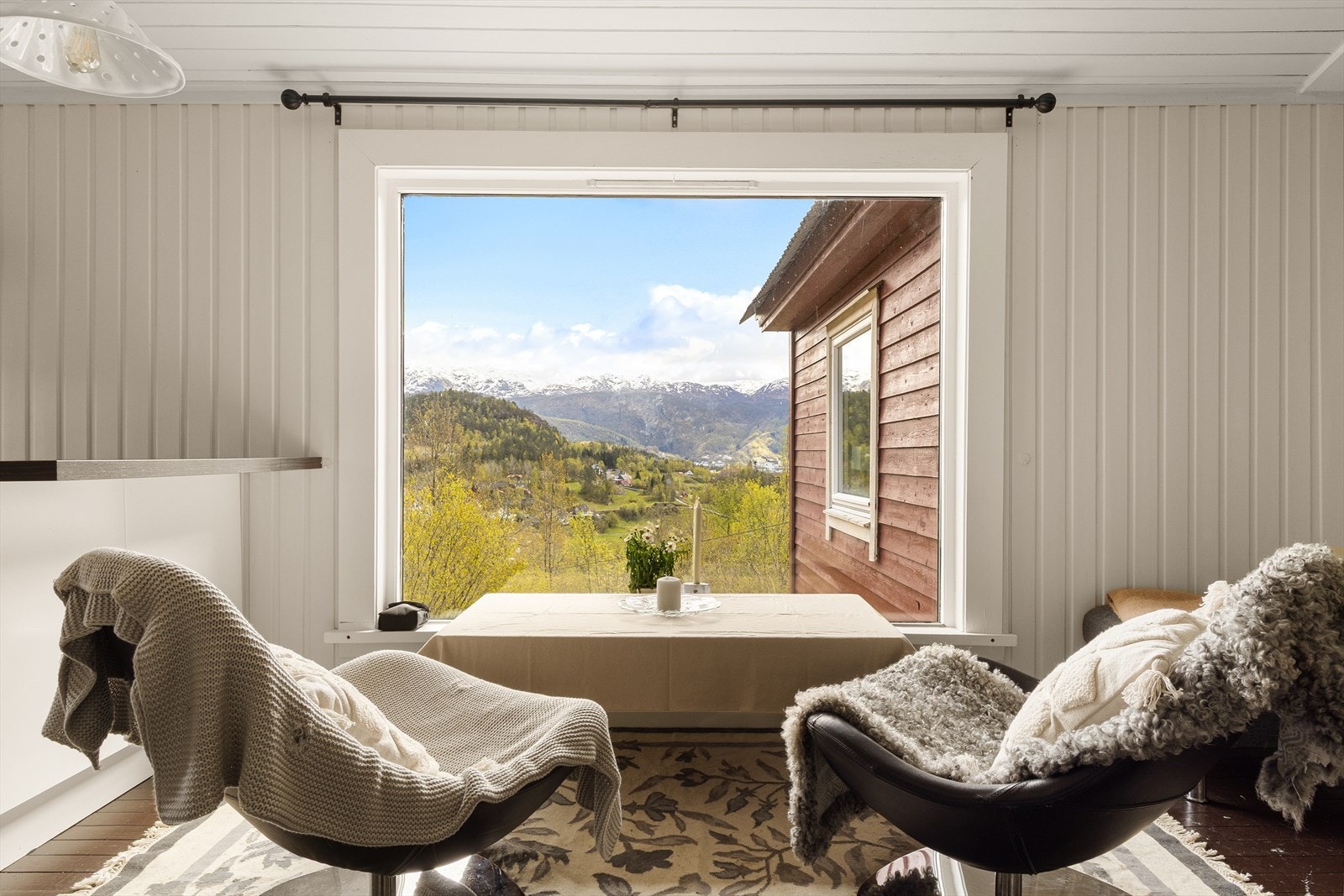 Vindusflatene rammer inn en nydelig utsikt over nærområdet og omkringliggende fjell. Galleribilde
