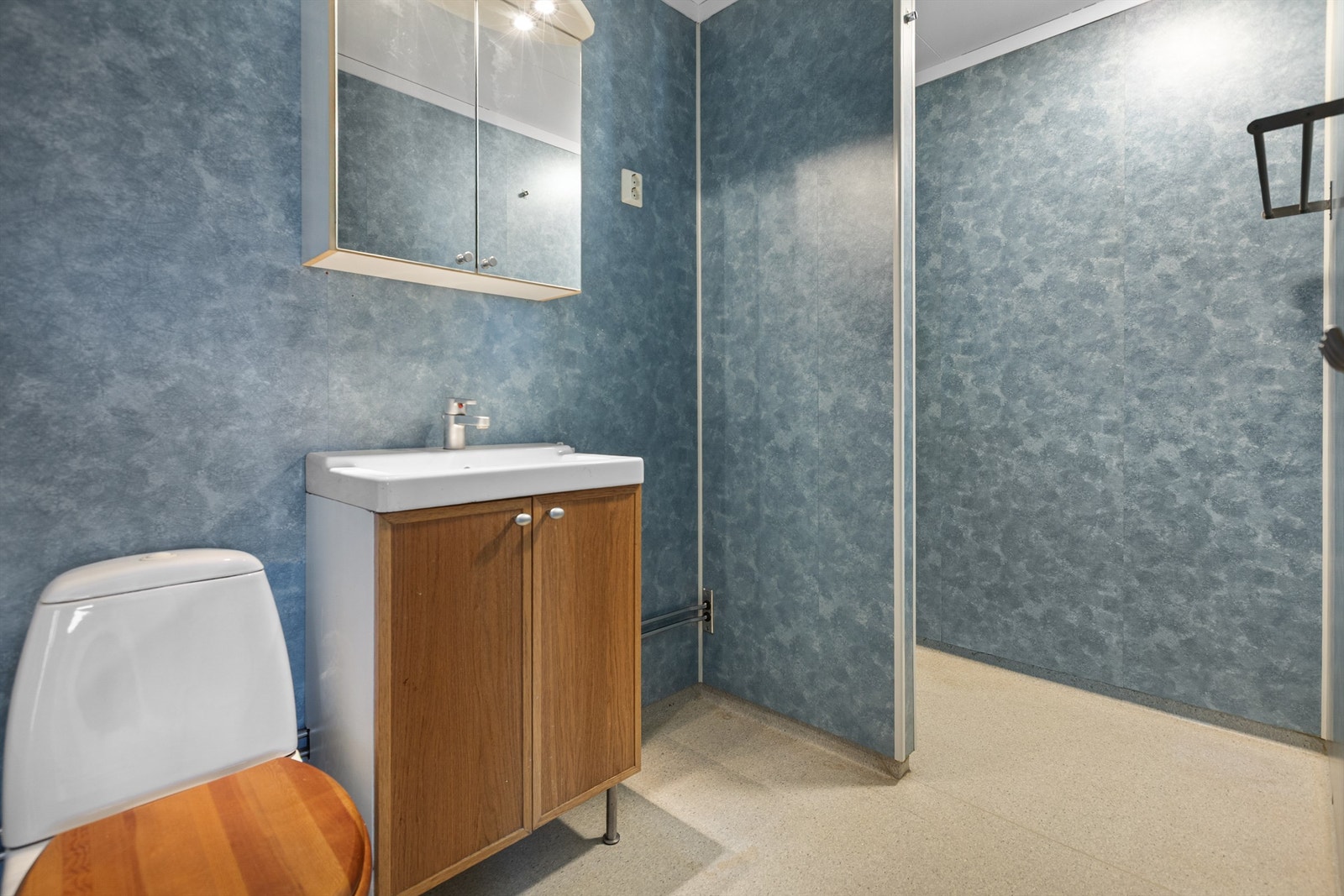 Badet er utstyrt med servantinnredning, speilskap med belysning og gulvstående toalett. Galleribilde