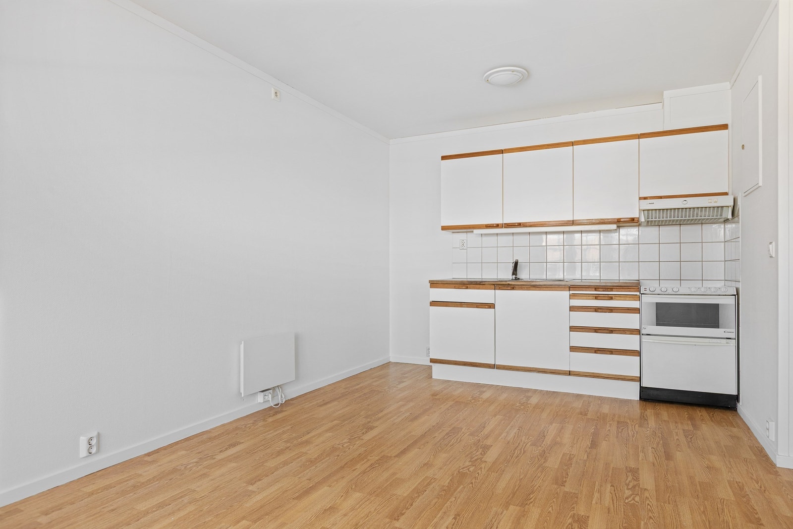 Kjøkkeninnredning med slette fronter og benkeplate i laminat. Det er ventilator med mekanisk avtrekk over komfyren. Galleribilde