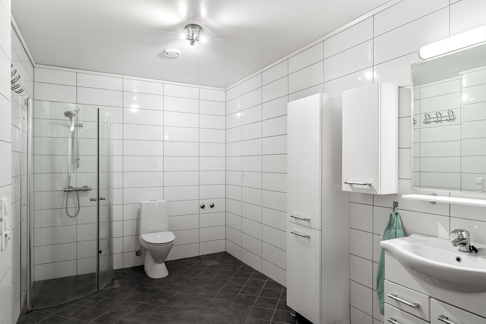 Badet har flislagt gulv med elektriske varmekabler og fliser på veggene. Galleribilde