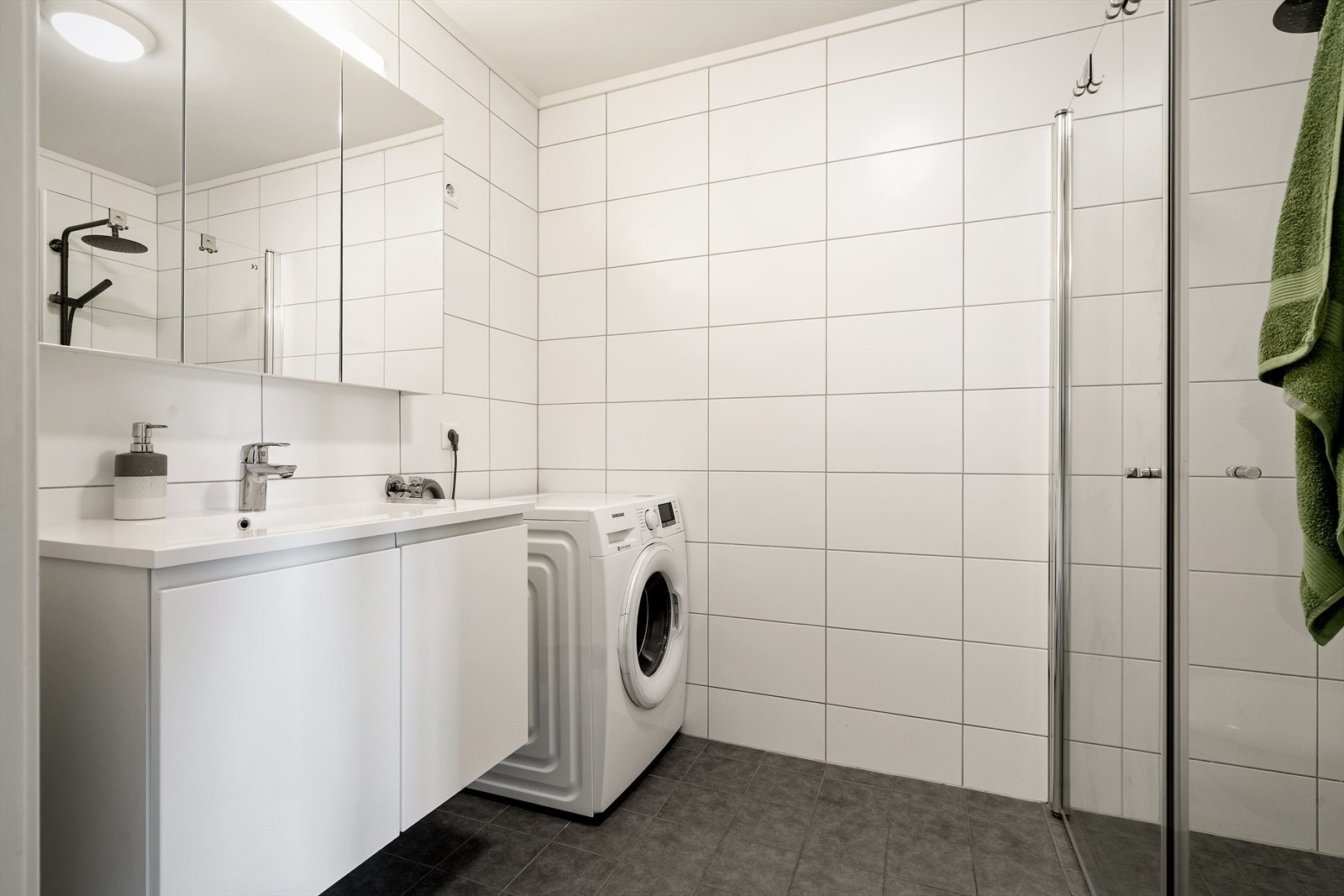 Badet er utstyrt med moderne innredning, inkludert veggmontert toalett og servant med skap. Galleribilde