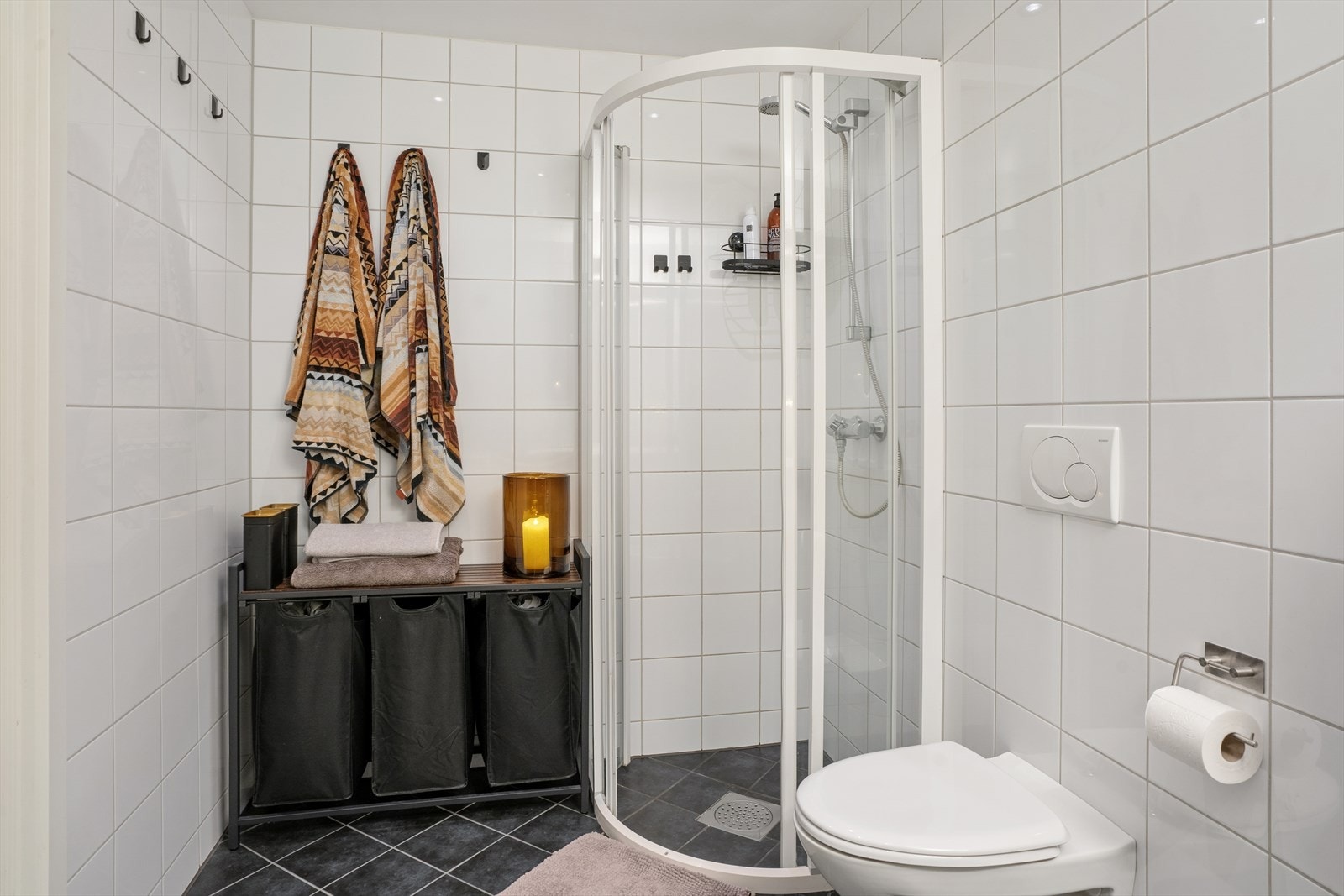 Badet er utstyrt med vegghengt toalett, dusjhjørne, samt baderomsinnredning med servant og speil. Galleribilde