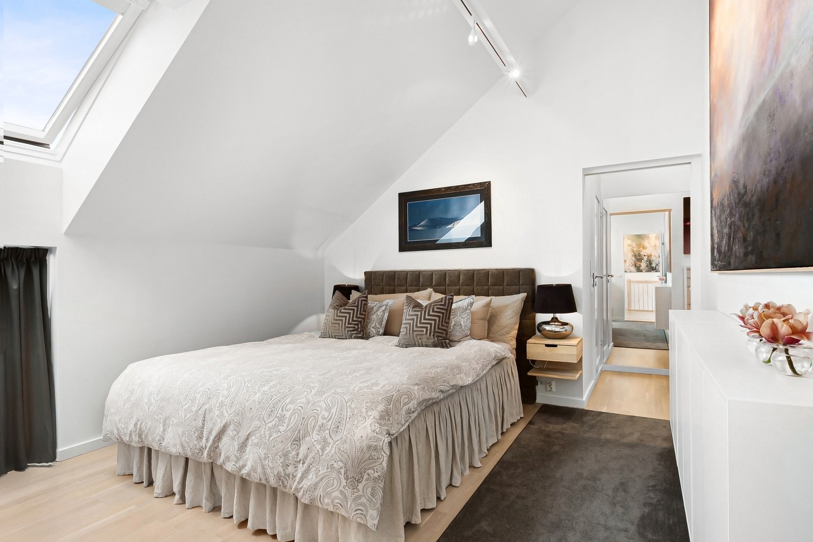 God plass til stor seng og nattbord på begge sider. Går man videre innover har rommet tilgang til eget bad t.v., og walk-in closet t.h. Galleribilde
