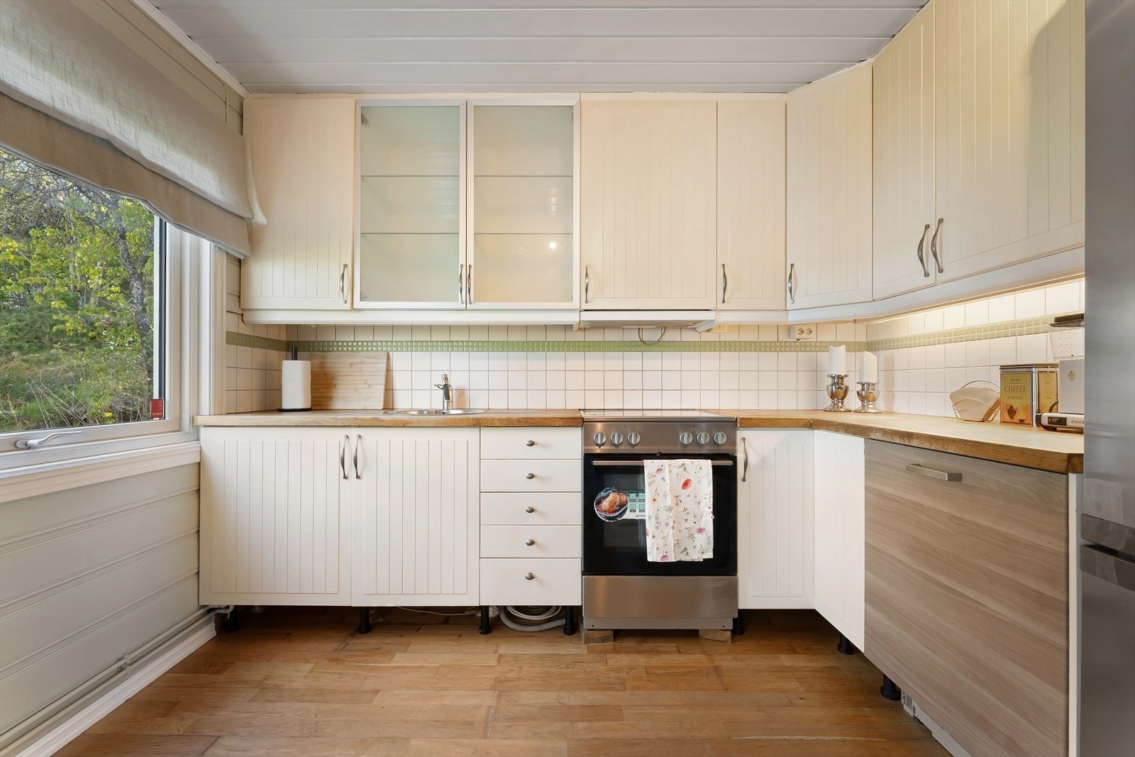 Profilerte og glatte fronter samt enkelte frostete glassfronter i overskap. Fliser på vegg og heltre benkeplate. Ventilator med avtrekk gjennom yttervegg og opplegg for vaskemaskin. Galleribilde