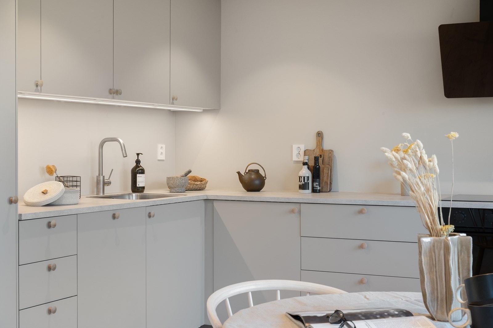 Ny, delikat kjøkkeninnredning med laminert benkeplate, slette fronter og nedfelt stålvask. Galleribilde