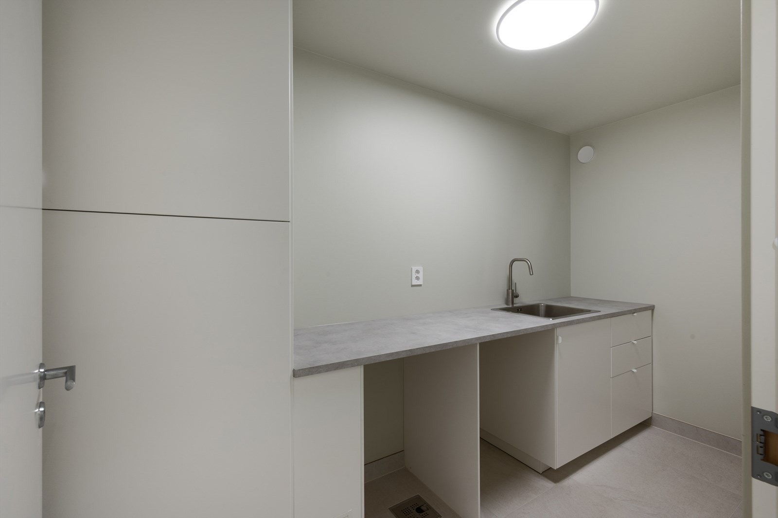 Praktisk vaskerom med benkeplate, nedfelt stålvask og rikelig med oppbevaringsplass. Galleribilde