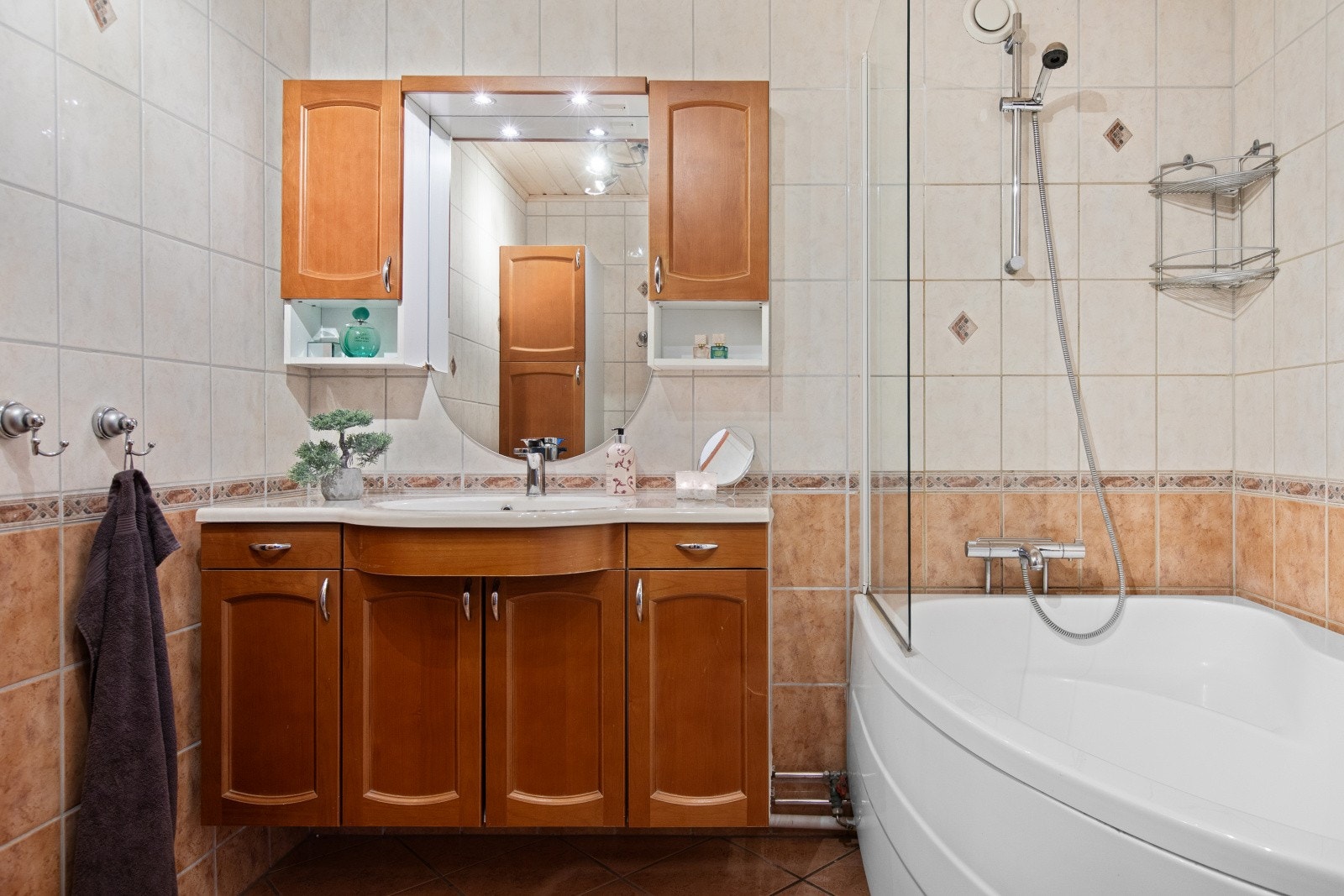 Badet har fliser på gulv og vegger, badekar og gulvvarme. Det er godt med oppbevaringsplass i baderomsinnredning. Galleribilde