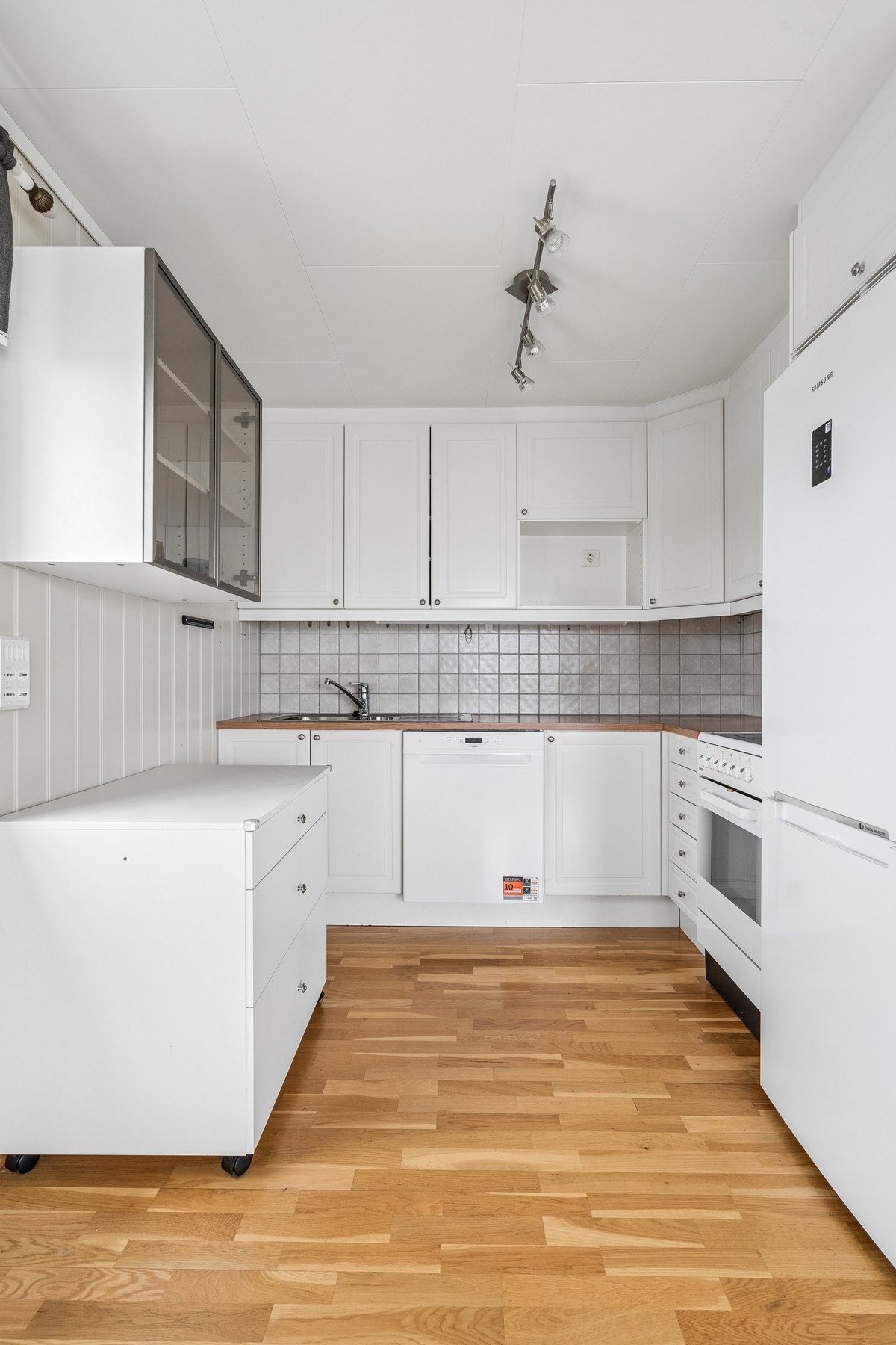 Praktisk kjøkken med hvite, profilerte fronter og laminat benkeplate. Galleribilde