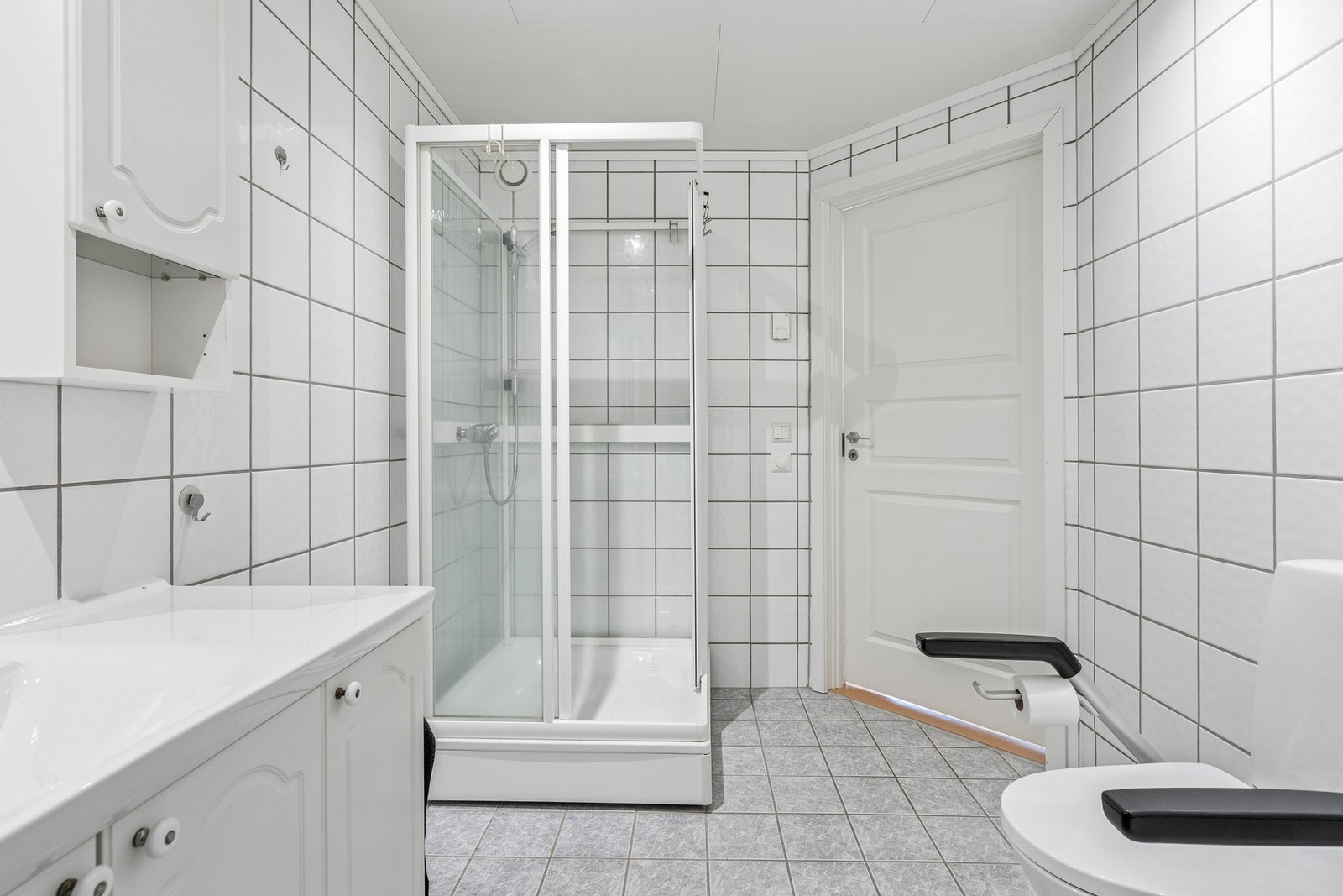Badet er romslig og praktisk utformet med lyse, tidløse fliser. Galleribilde
