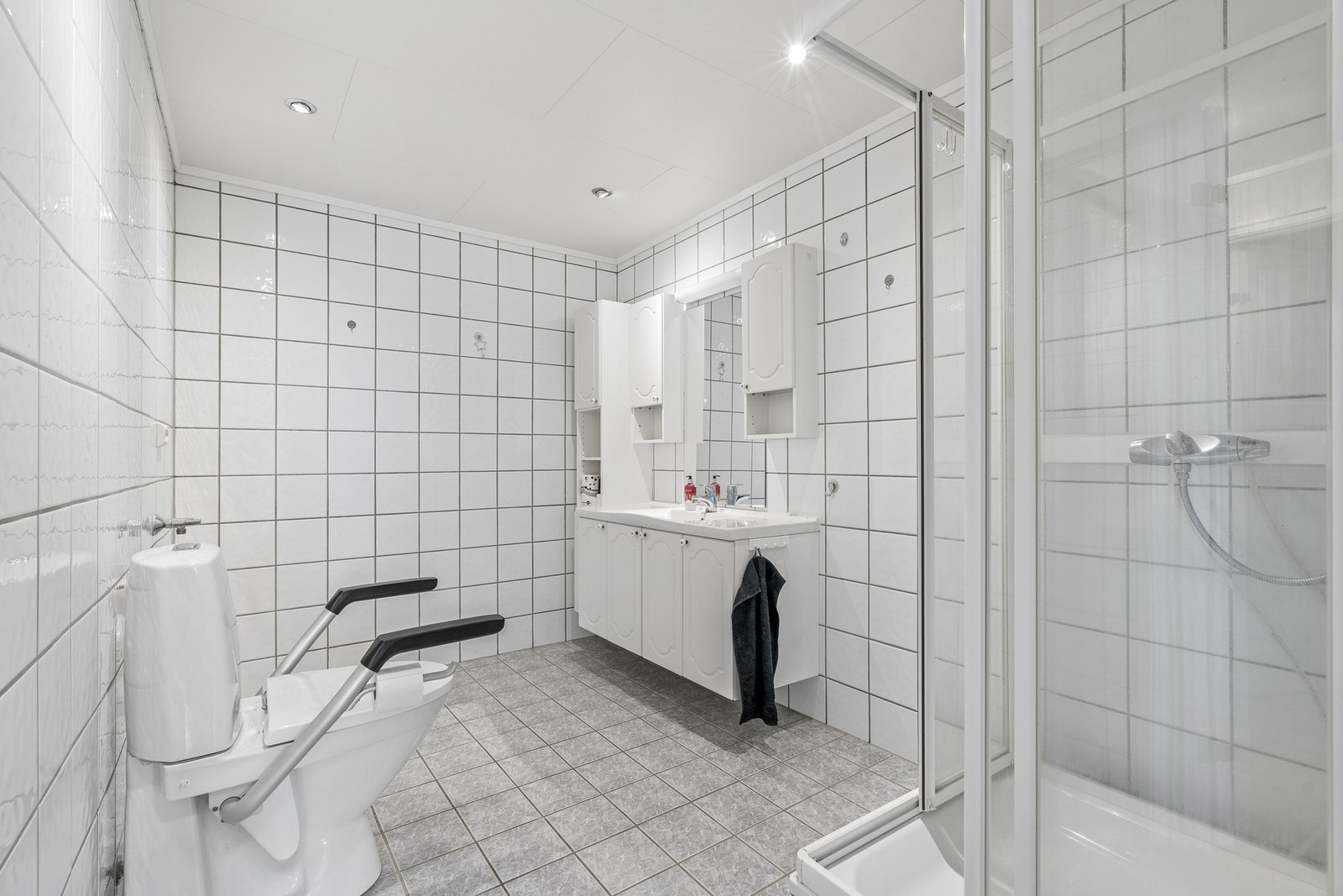 Helfliset bad med gulvvarme, innredet med servantmøbel, toalett og dusjkabinett. Galleribilde